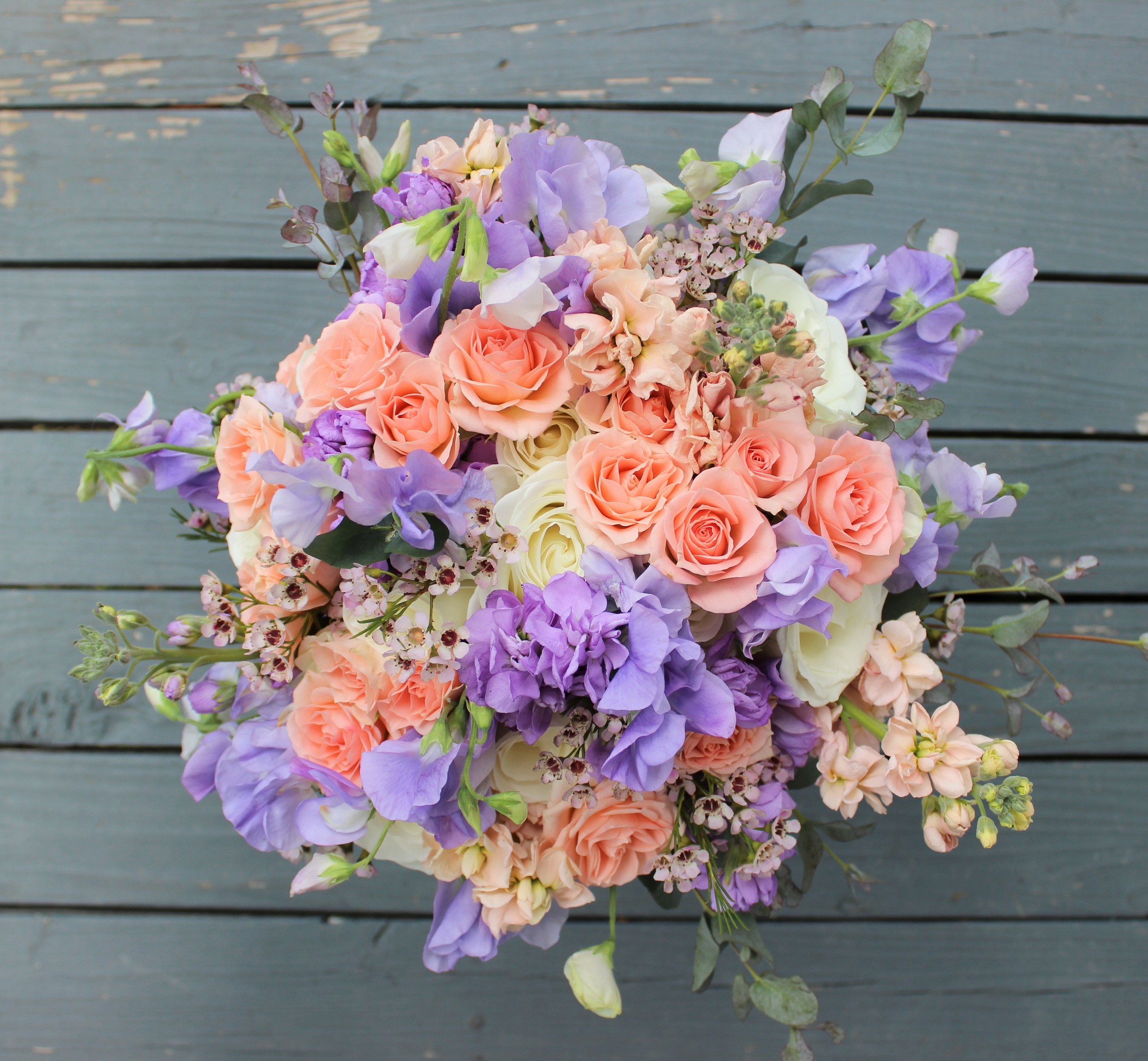 The bride's bouquet contained ivory roses, peach spray roses, lavender sweet peas, peach & lavender stock, wax flower and gunni eucalyptus. We chose these flowers based on Nicole's color palette and style along with seasonal flower availability. We were lucky to get these gorgeous sweet peas! They are so fragrant and delicate in person. Photo by The Floral Cottage