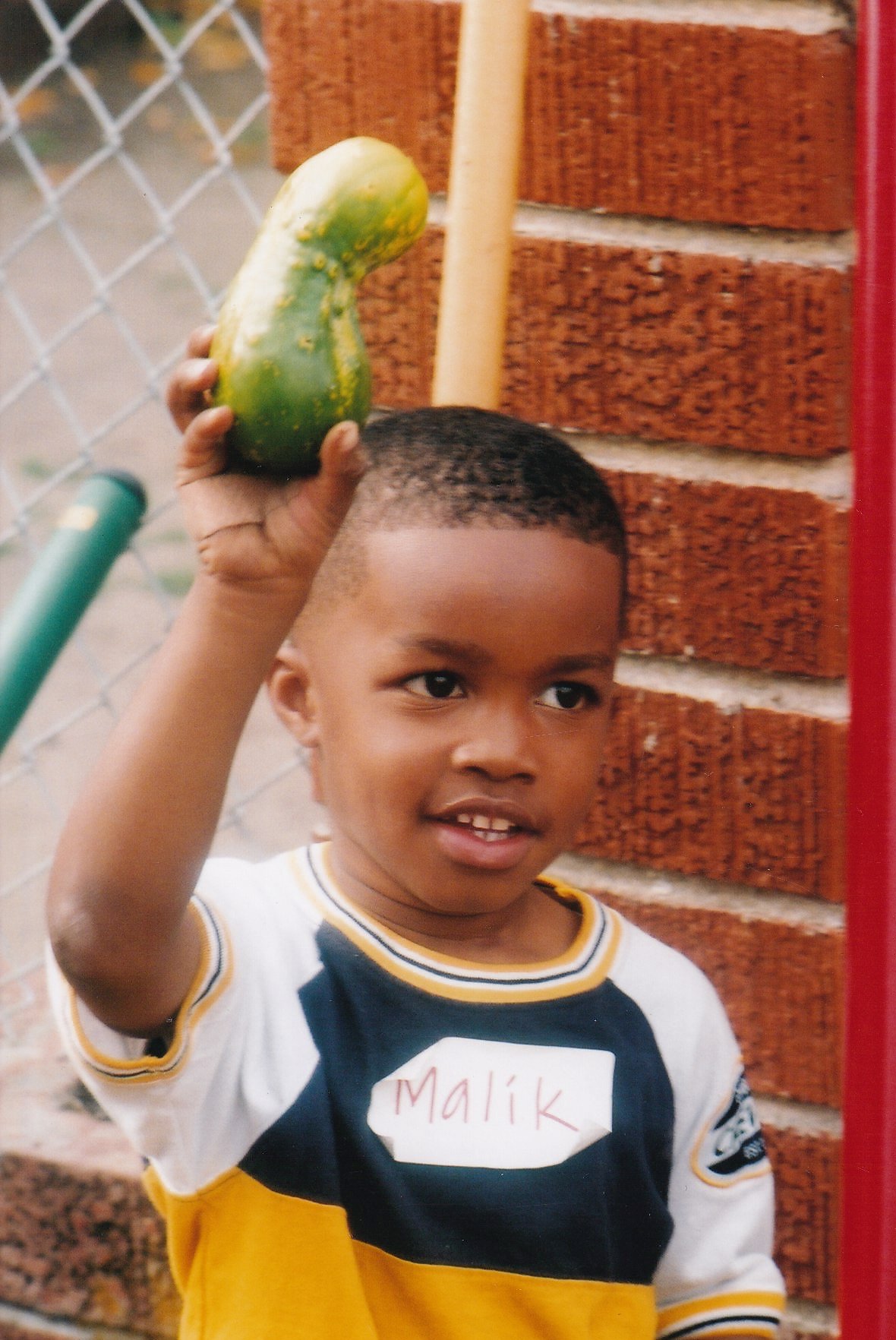   ArtEsteem youth holding a cucumber grown in the garden at 3278 West Street.  