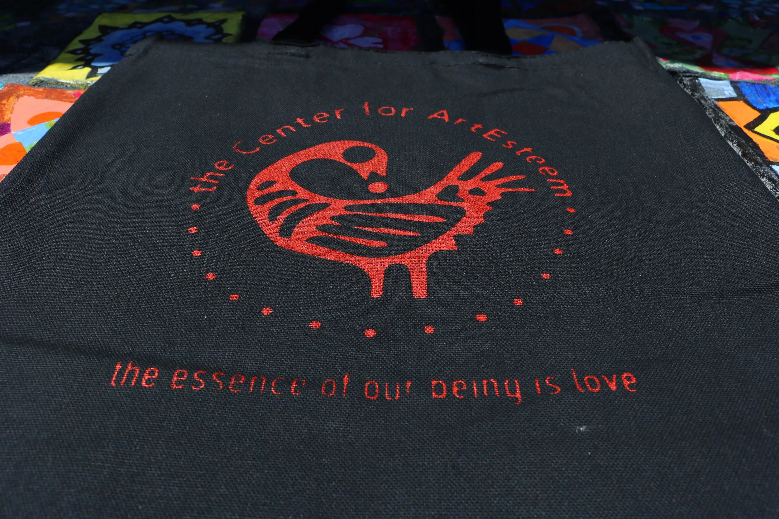  The result of a screen printed tote bag. The design is a Sankofa bird in place of ArtEsteem's heart logo, with Attitudinal Healing Principle #1, "The essence of our being is love." written below.  This activity was co-led by Program Assistant Darius
