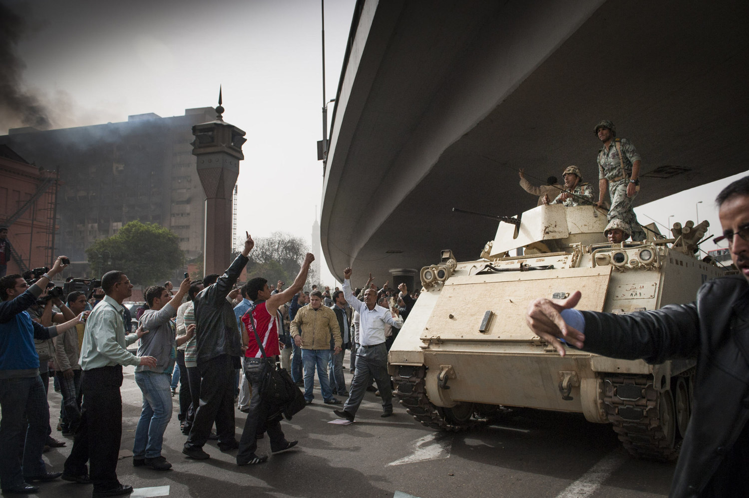  Crowds cheer on the military as they enter the square as government building in the background still smolder from the "Day of Rage" on January 29, 2011. 