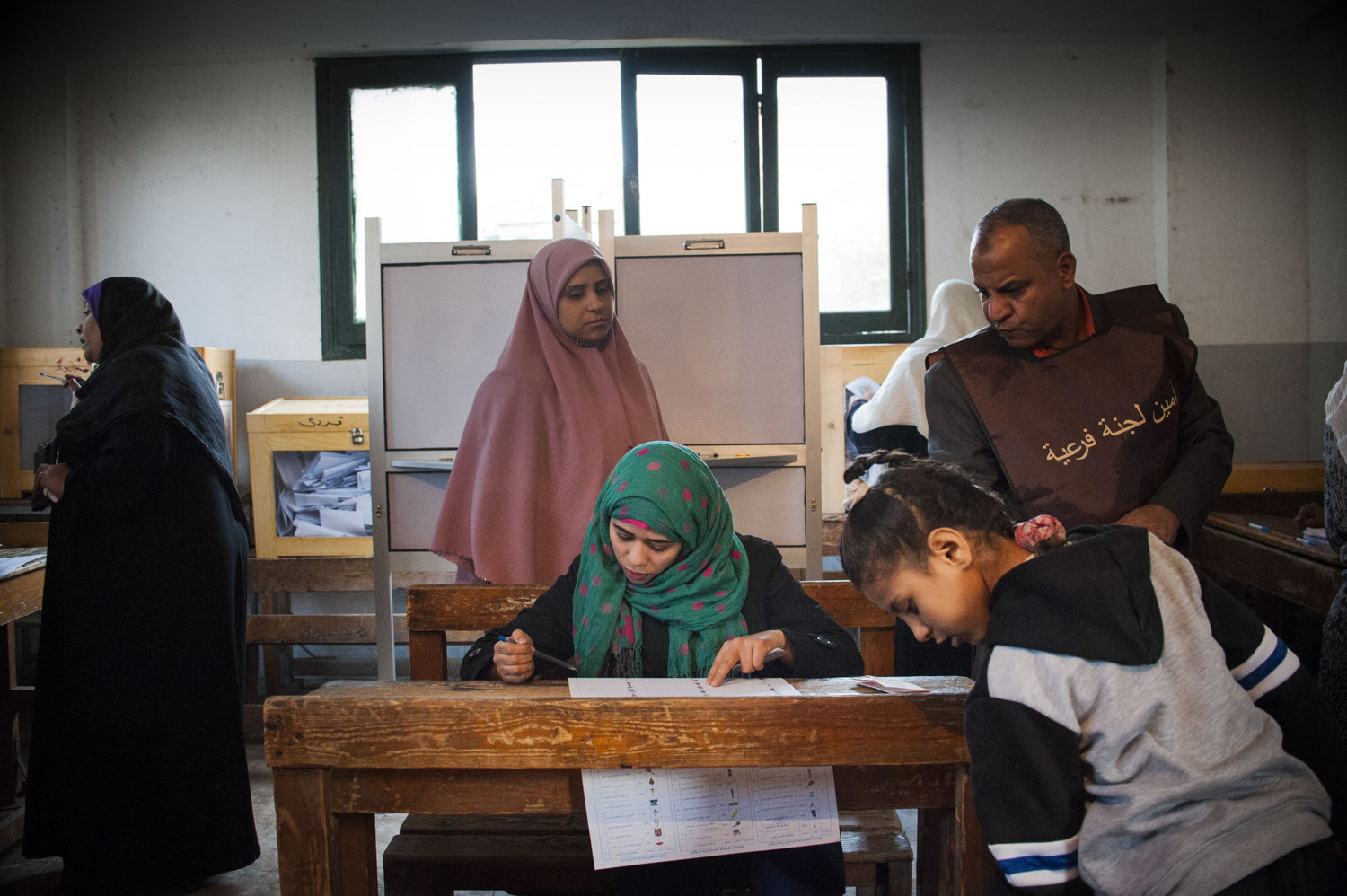  A woman fills out her ballot while an election worker looks over her shoulder on November 28th, 2011. 