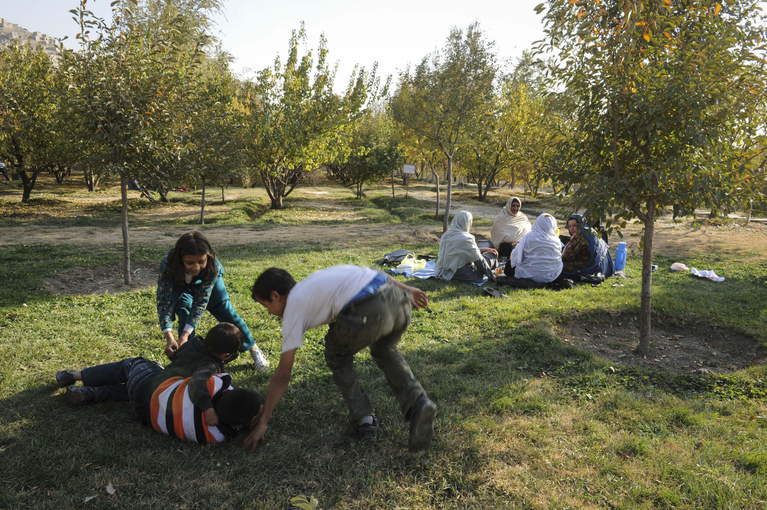  Children play on the grass at Bagh-e Babur historic park in Kabul Afghanistan while mothers watch nearby. The park is also the last resting-place of the first Mughal emperor Babur.  
