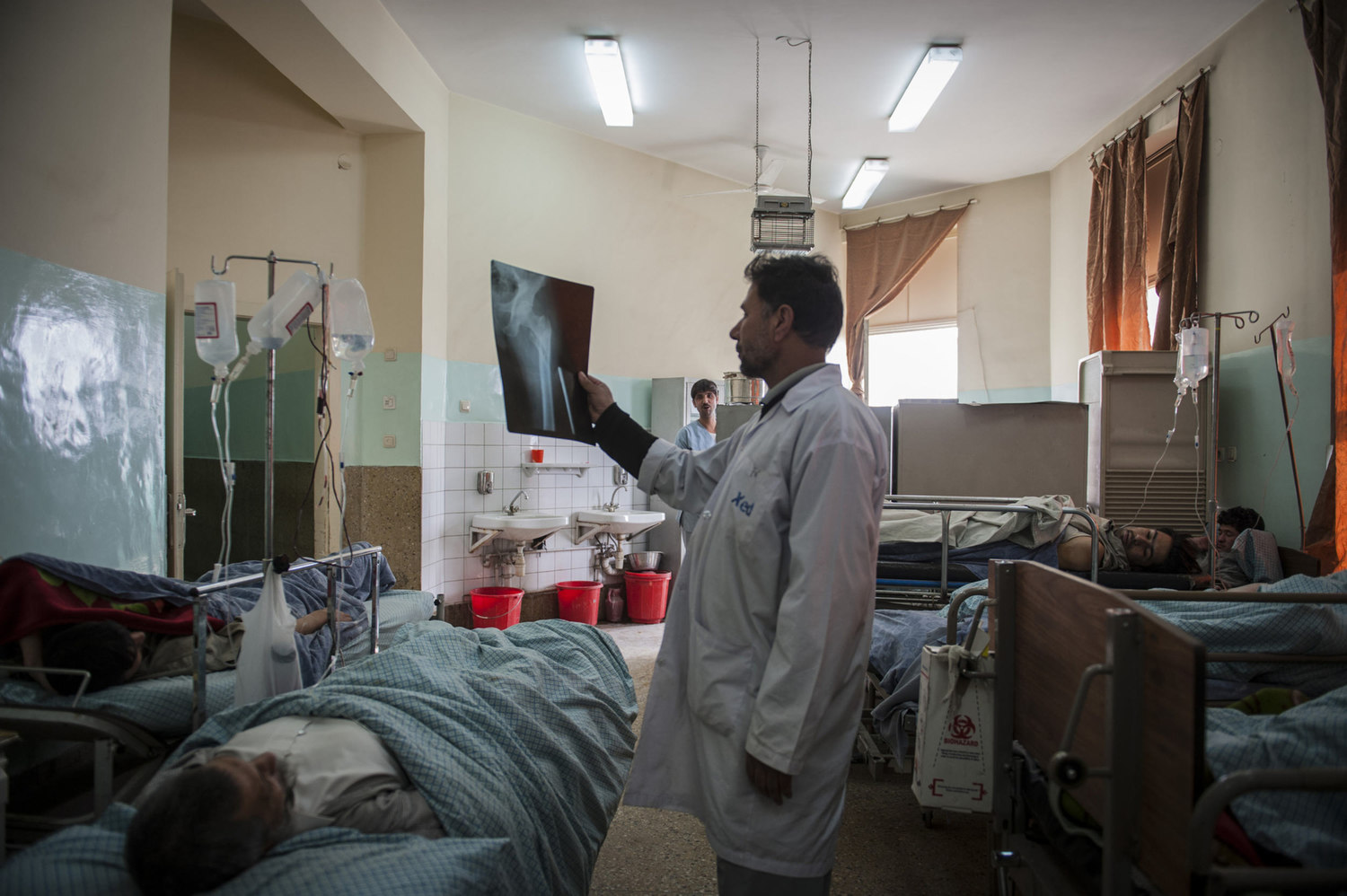  Dr.Younis examines a patients x-ray in the mens orthopedic ward at Wazir Akbar Khan Public Hospital in Kabul Afghanistan. Some hospital rooms hold up to 25 patients, using all available space. Many patients also rest in the hallway. 