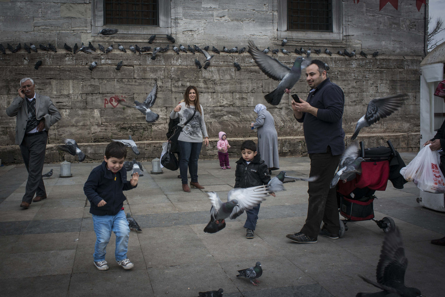  A boy feeds birds while his family watches outside of 'Yeni Cami' or New Mosque in the Eminönu section of Istanbul. Interestingly the Yeni Cami is one of the oldest mosques in Istanbul, but was considered 'new' when construction started in 1597. 