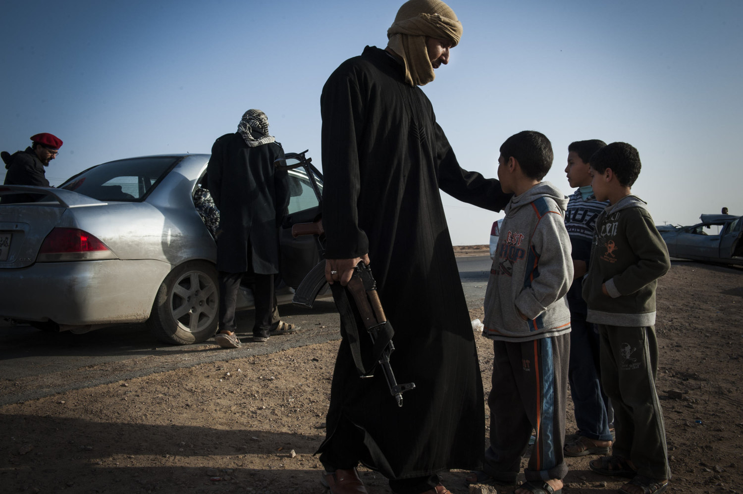 A man and his sons watch as fighters load into a car and head south to the battle. 