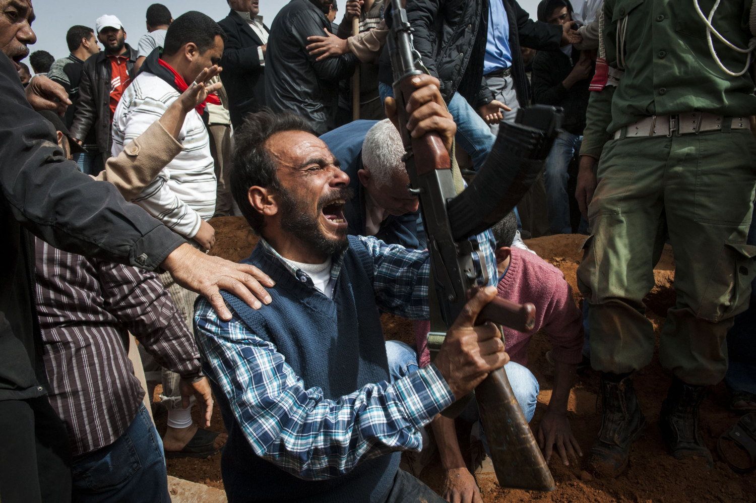  Men attend a mass burial at Benghazi Cemetery for seven men killed in an armory explosion the night before. It's not clear if the armory exploded due to airstrikes or error by the soldiers. 