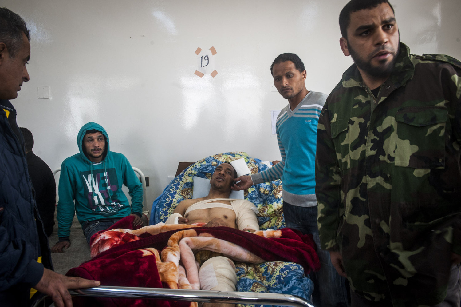  A man calls his family while friends attend to him in the hospital in Benghazi, Libya. 