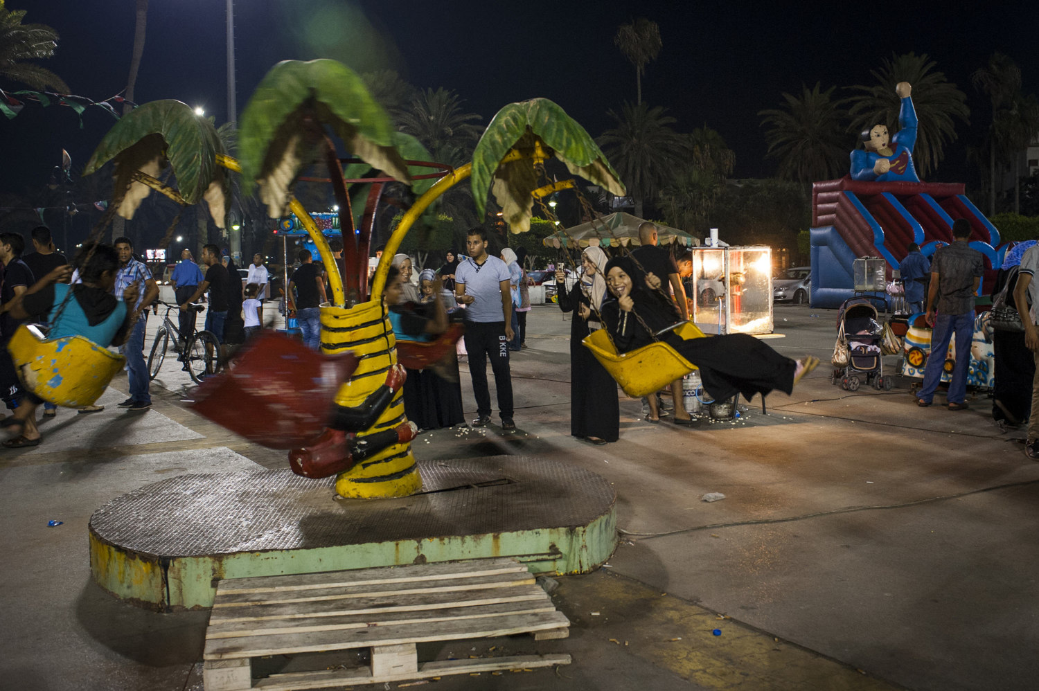  Children enjoy themselves on a ride in Martyr's Square in Tripoli, Libya. Public spaces morph into amusement parks during the summer months in Libya as the heat keeps many indoors all day. 

 
