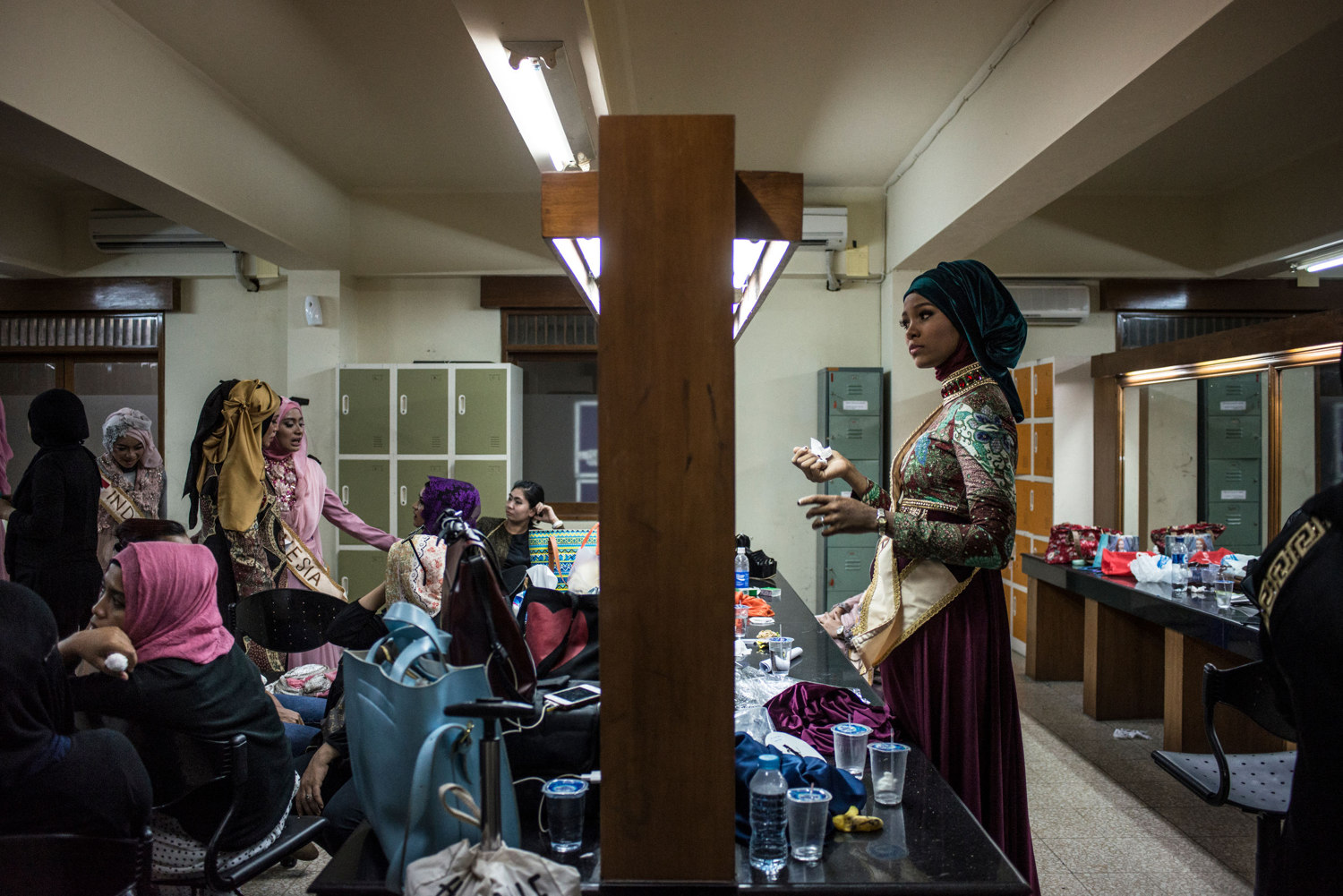  After advancing to the second round, Miss Nigeria, Bilqis Adebayo, drinks water while stylists work on her hijab. The Grand Finale of the Miss Muslimah World Competition on November 21st, 2014 in Yogakarta, Indonesia. 