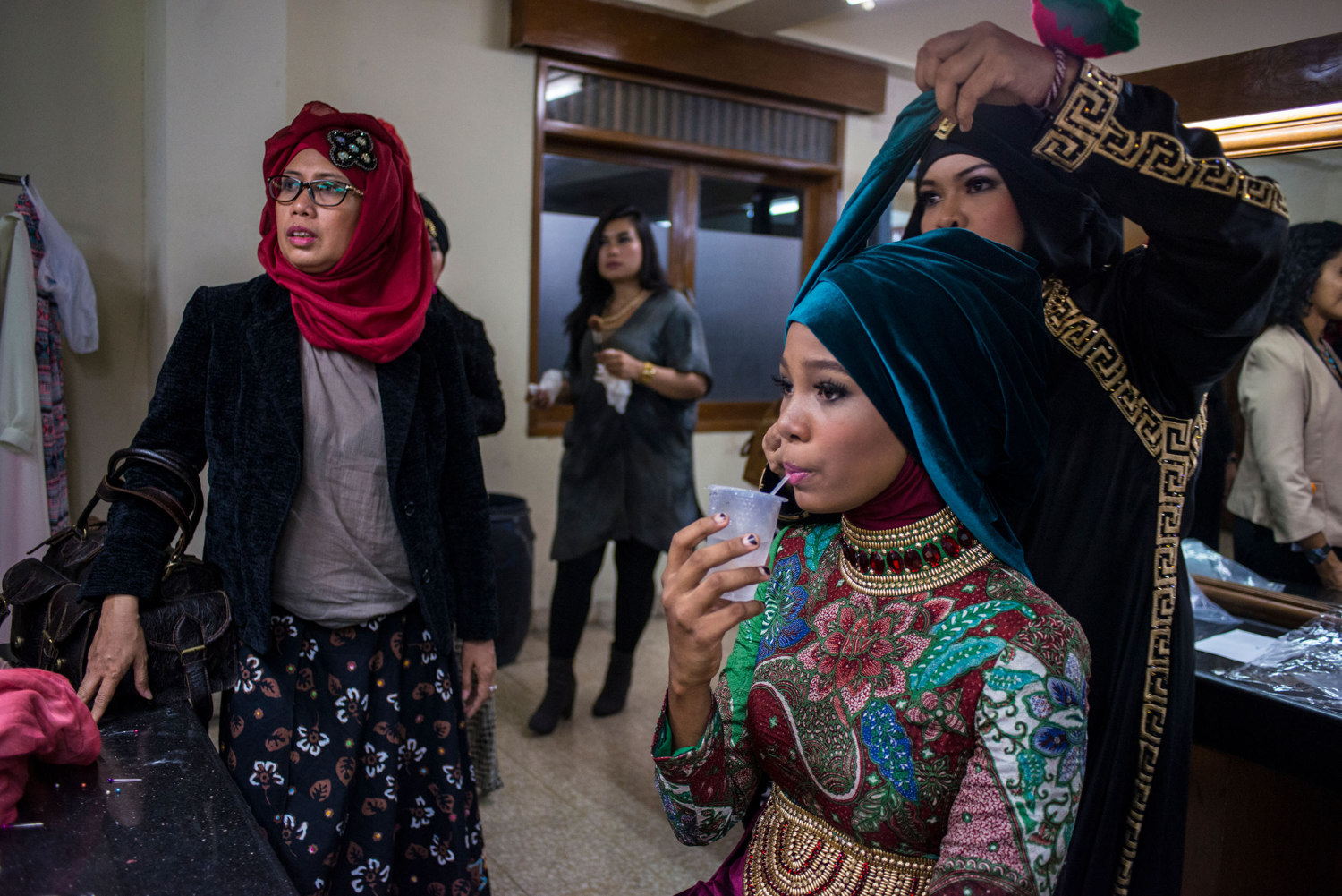  After advancing to the second round, Miss Nigeria, Bilqis Adebayo drinks water while stylists work on her hijab. The Grand Finale of the Miss Muslimah World Competition on November 21st, 2014 in Yogakarta, Indonesia. 