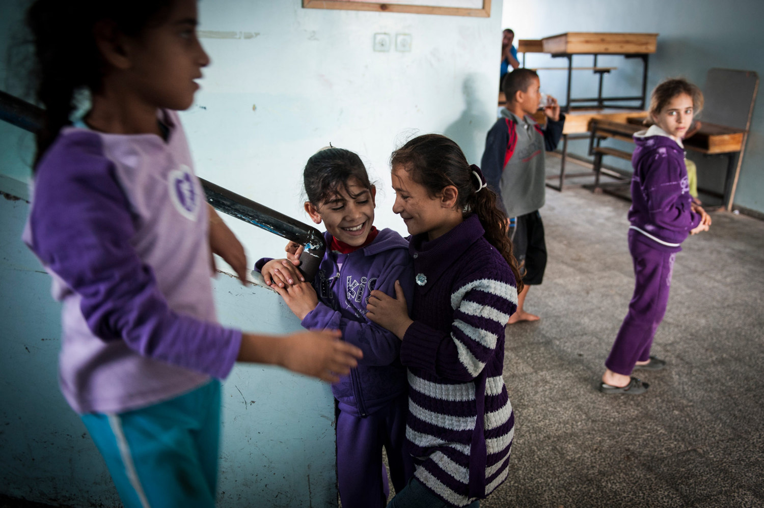  Girls living in a UNHCR shelter share a brief moment of fun between the shelling. In November 2010 when the Israeli Army heavily bombed parts of Gaza, refugees waited the siege in a United Nations Relief Works Agency school in Gaza City. 