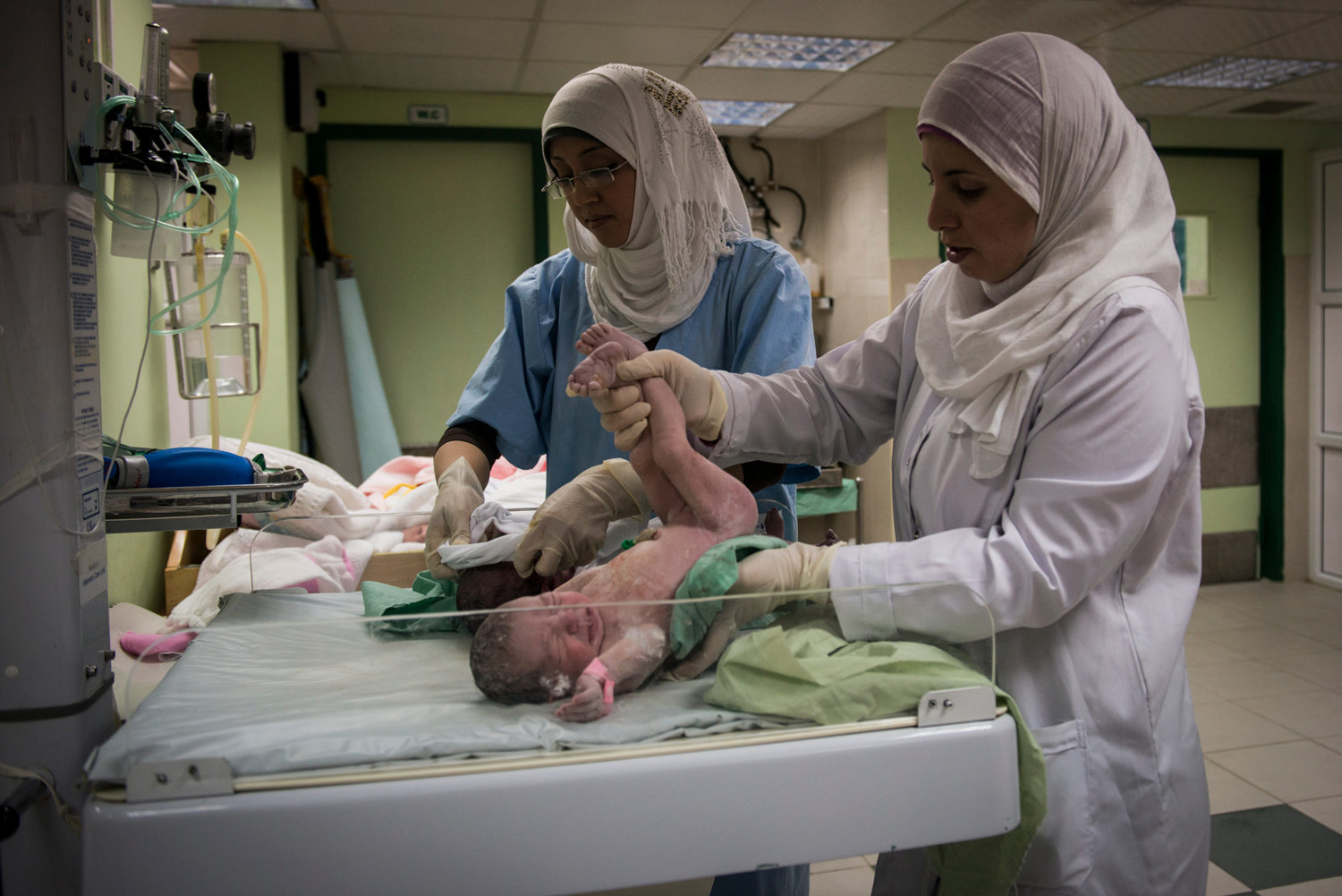  Nurses at Al-Shifa hospital clean and weigh two newly born baby girls. As most families put pressure on having many male children, the arrival of a girl is celebrated, but not as much as a male child as males are the heads of the house and breadwinn