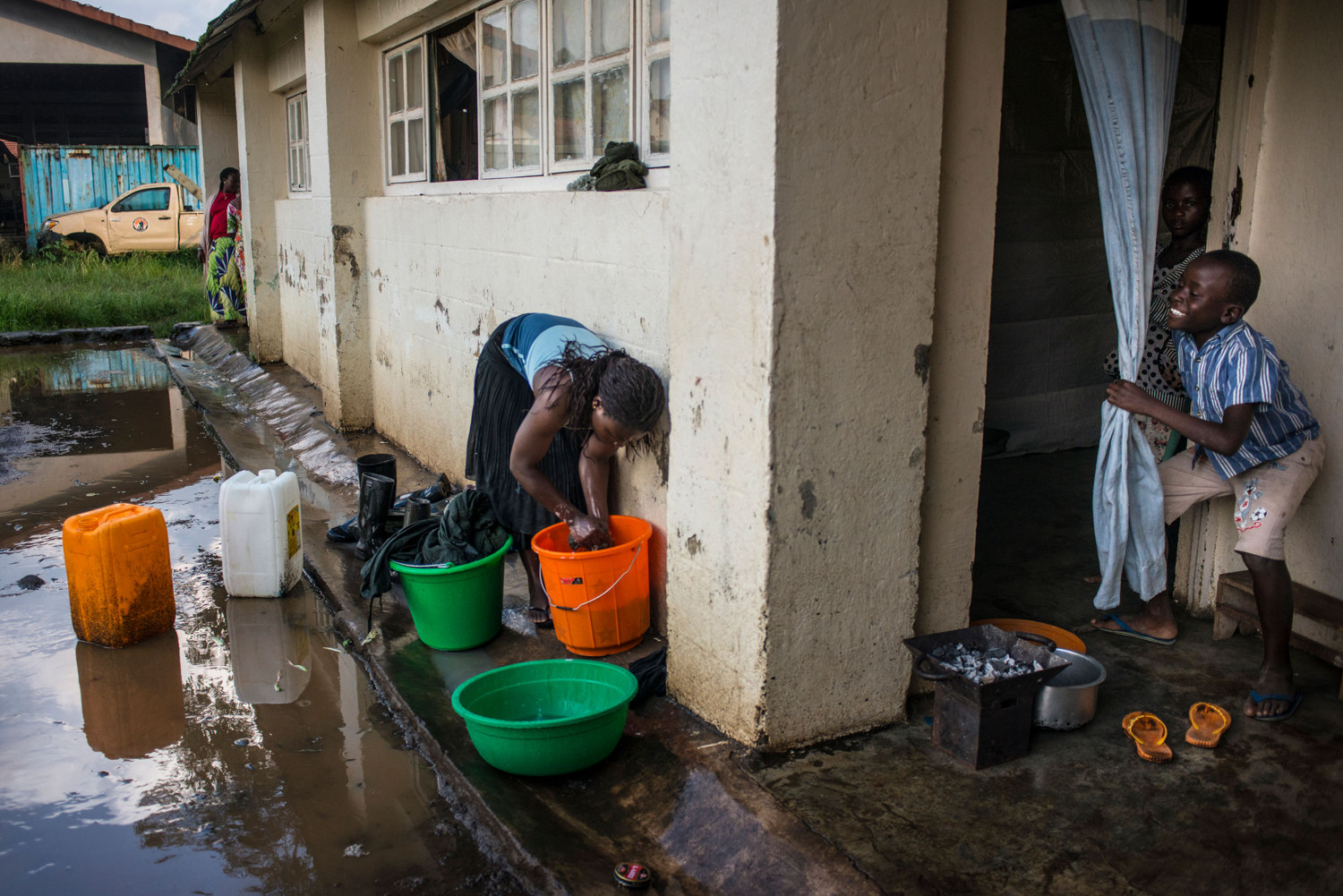  Solange washes clothing during a rainstorm in front of the room she shares with Solange. The house also has apartments for ranger's families.
 