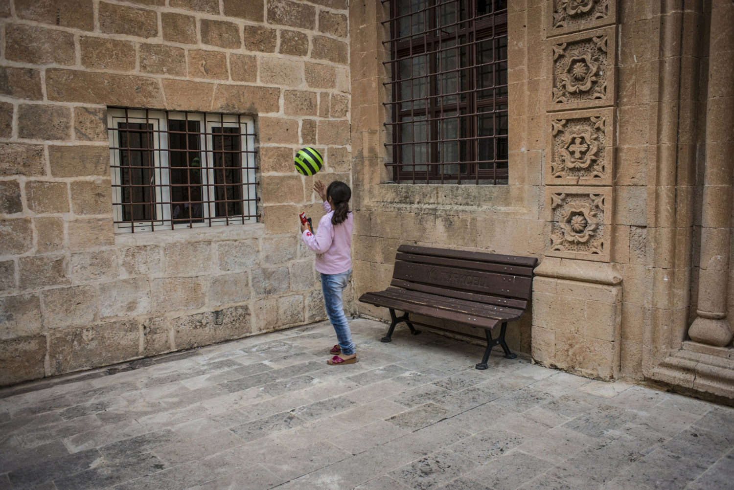  An Assyrian girl plays with a ball on the walls of the church of Mor Barsaumo before her Aramaic lesson on October 30th, 2014. 