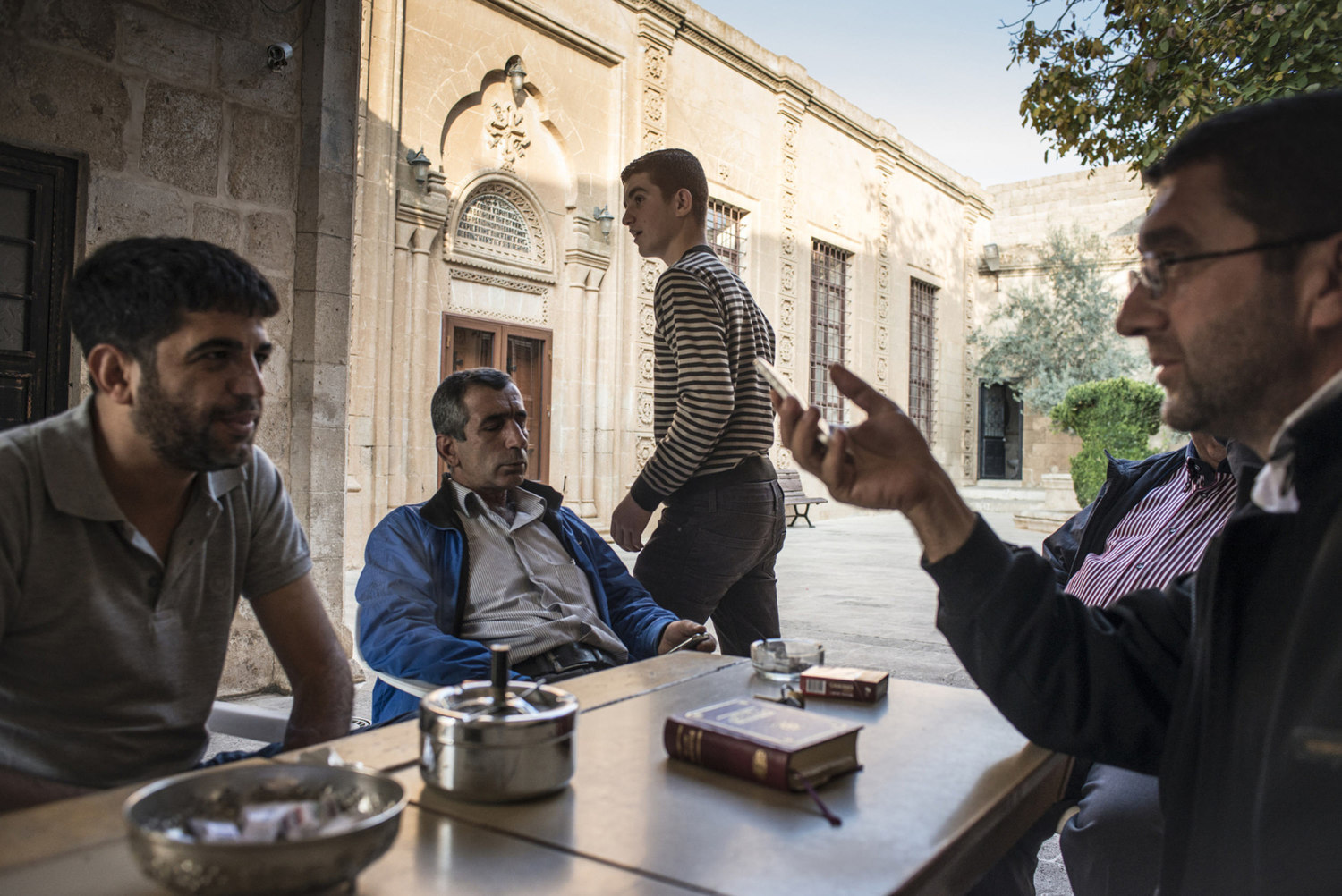  Decon  Ayhan Gürkan,(r) speaks to locals in the cortyard of Mor Barsaumo before teaching an Aramaic lesson on October 30th, 2014.

The Mor Barsaumo church is over 1,500 years old and was renovated in 1943. It is located 21 Şen Caddessi in Midyat, Tu