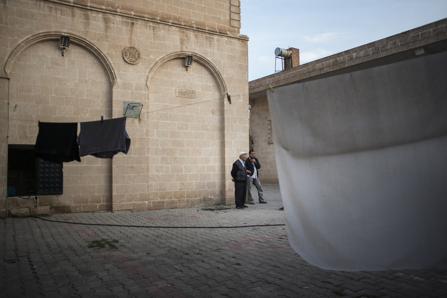  In the courtyard of the cultural center, Syrian refugees talk while laundry is drying on October 30th, 2014 in Midyat, Turkey. 