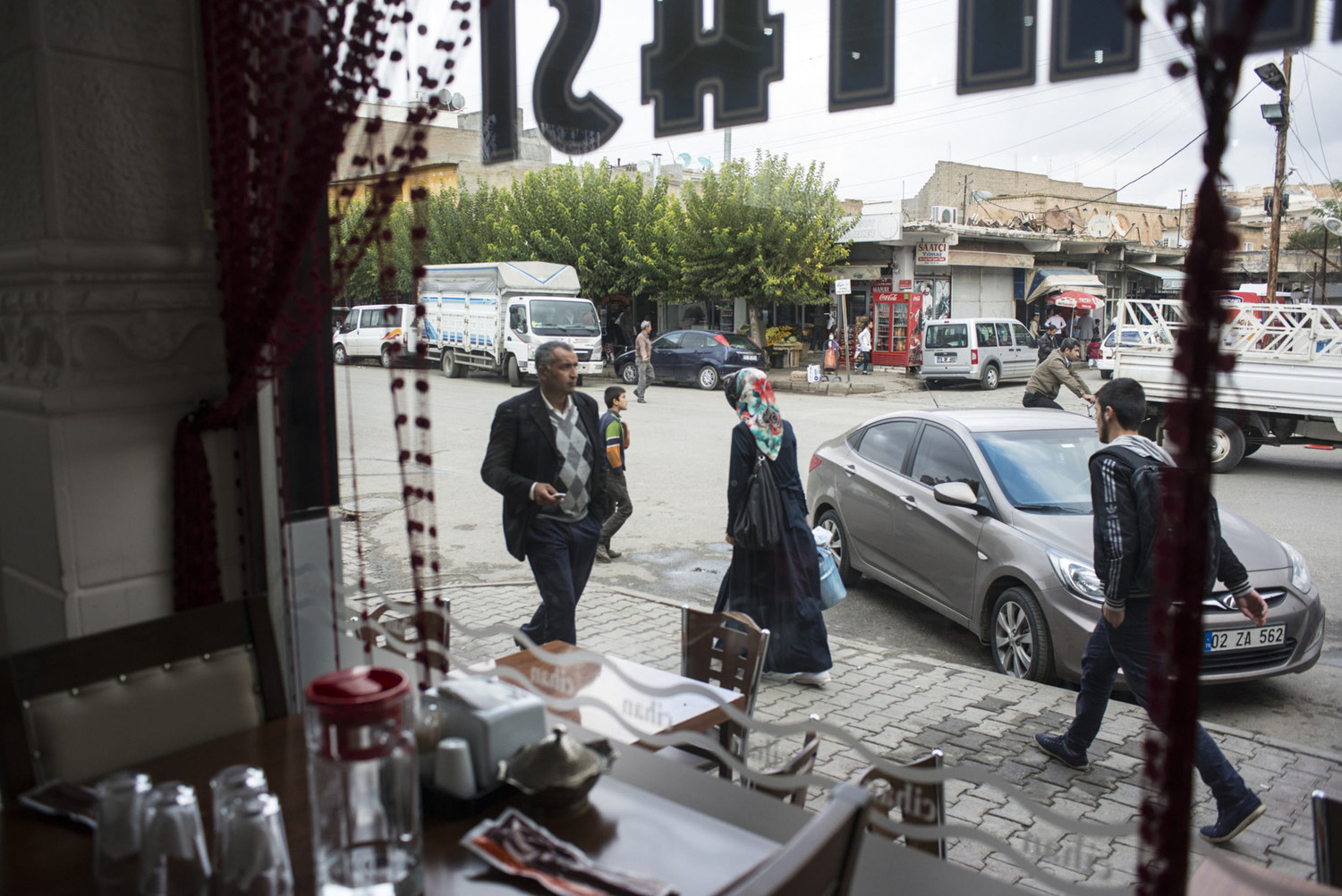  In downtown Midyat, a city with a mixed population of Turks, Syriac's and, Armenians. Through the window of a restaurant a woman walks down the main street on October 31st, 2014. 