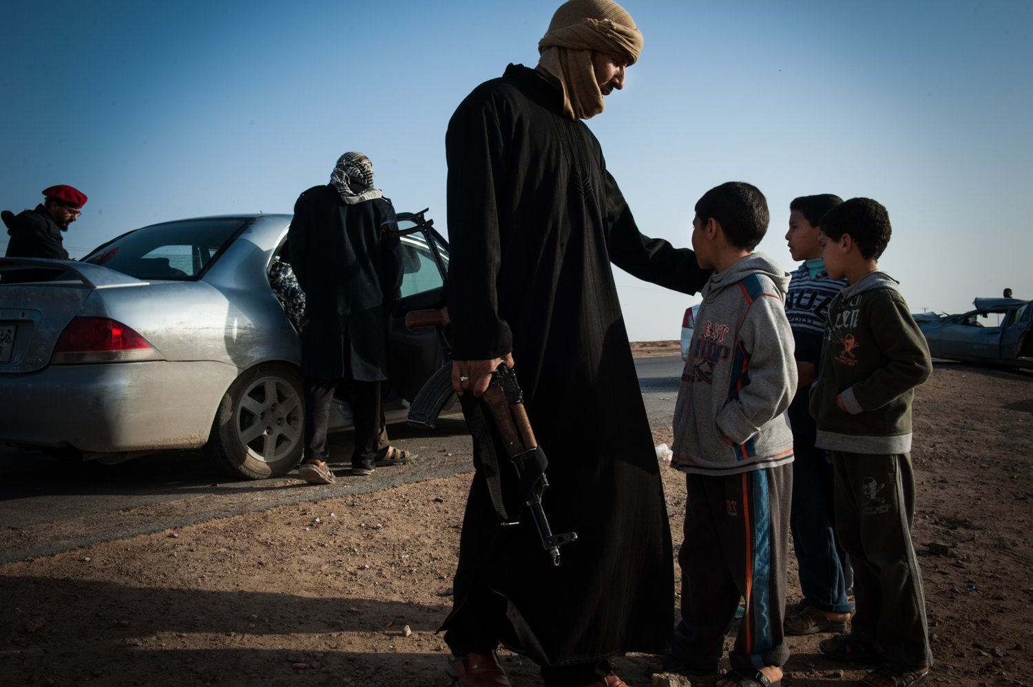  A man and his sons watch as fighters load into a car and head south to the battle in Libya, 2011.  