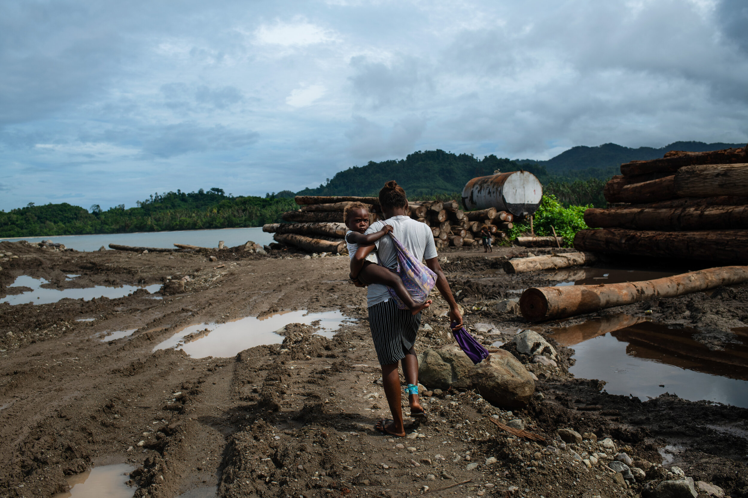  A woman walks through a logging camp used by the Apex company on September 23rd, 2019. These logging points are crucial for moving round logs to ships and out of the country. Because these points are so remote it makes it difficult to police whether