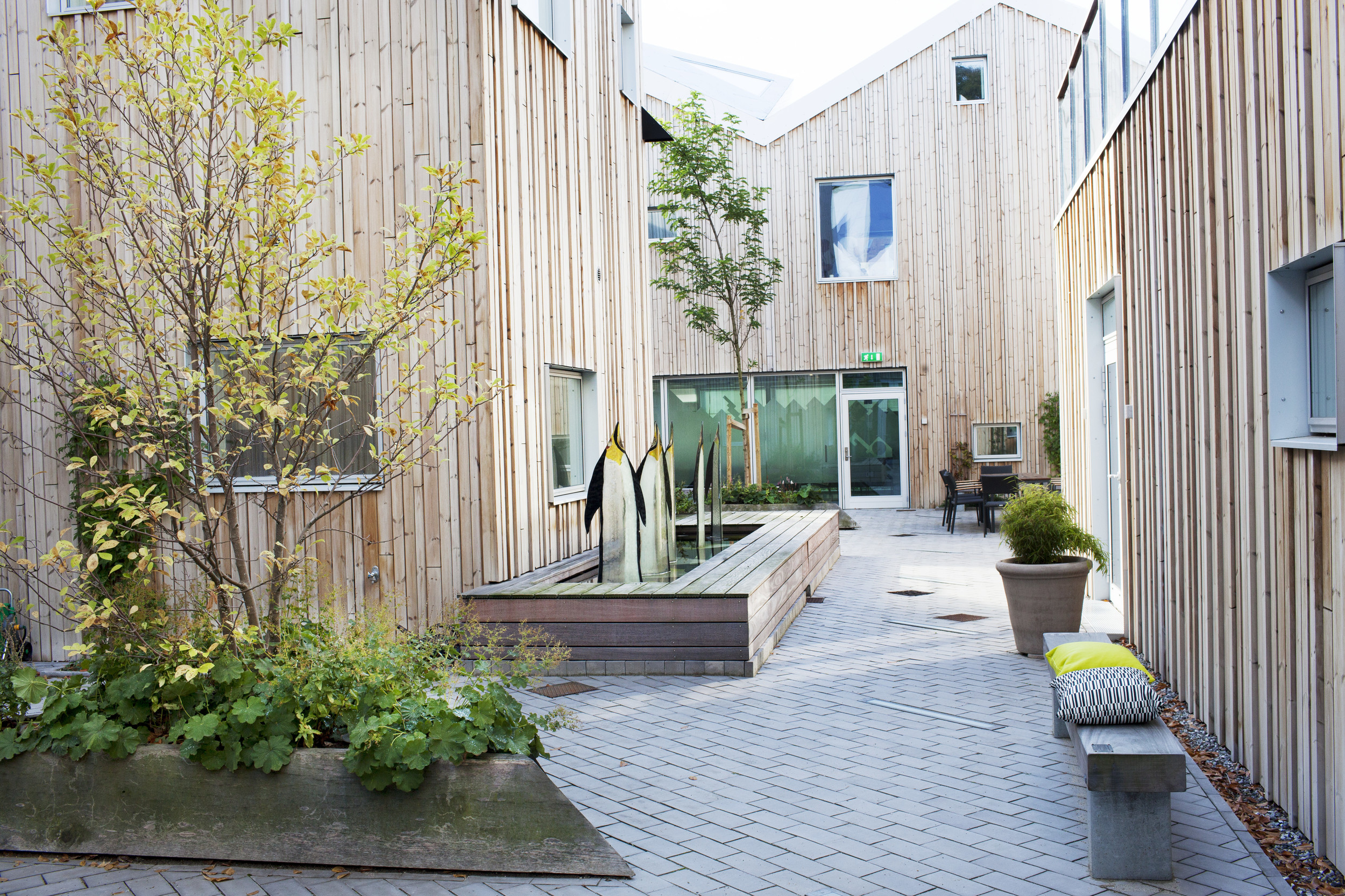 I den indre gård erstattes de metalliske yderfacader med lameller i blødt træ. Glaskunsten er skabt af en tidligere patient. Foto: Center for Kræft og Sundhed