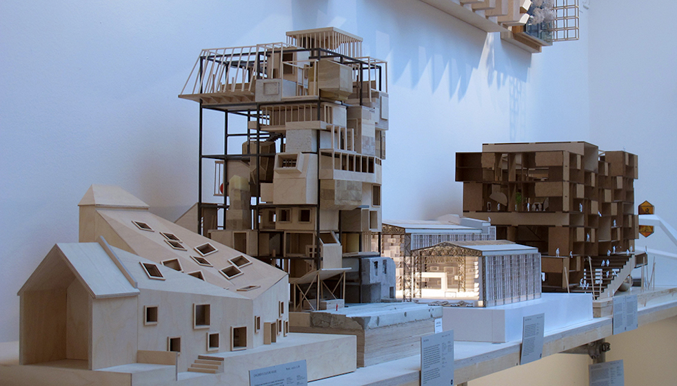 En Model ses i midten med den firkantede metalgitterstruktur, hvorimellem de forskellige og frit definerbare typologier så kan udfoldes opefter. I arkitekternes udgave er der fx en børnehave og en hestestald i bunden, restaurant på toppen og en fuldt offentligt tilgængelig trappe i kernen af strukturen. Foto: Tyra Dokkedahl
