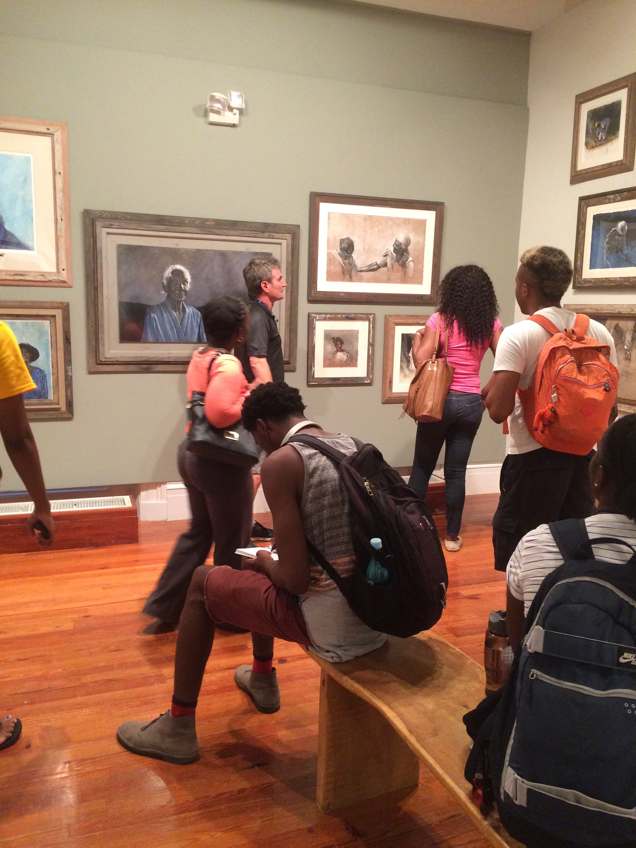 University of The Bahamas students visit Thierry Lamare’s “Love, Loss and Life” on view at the National Art Gallery of The Bahamas and receive a guided tour by the artist. Students ask questions and take notes of the images on view.
