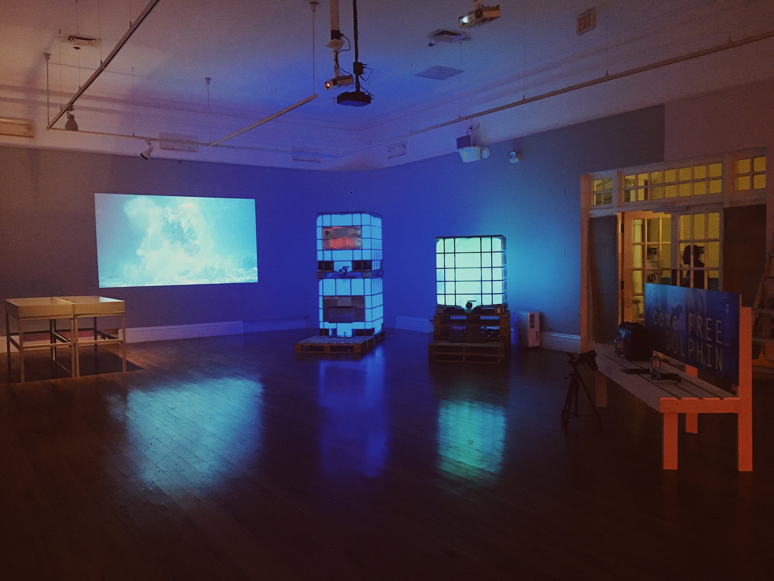 Installation shot of “Hot Water” with Digging Upwards in Sand, (2018) a video by the Plastico Fantastico Collective and Expected Time of Arrival: 6:30, (2018) installation by Expo 2020.