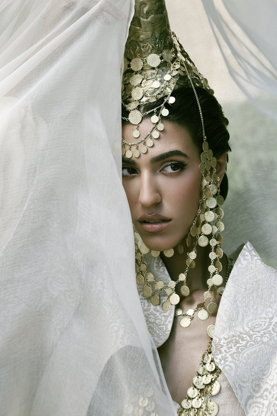 A classic 19th-century Lebanese princess ensemble featuring a Gambaz dress with side slits, worn over sherwel pants and topped with a traditional embossed silk brocade jacket. The look is completed with the iconic Tantour headdress, crafted from han