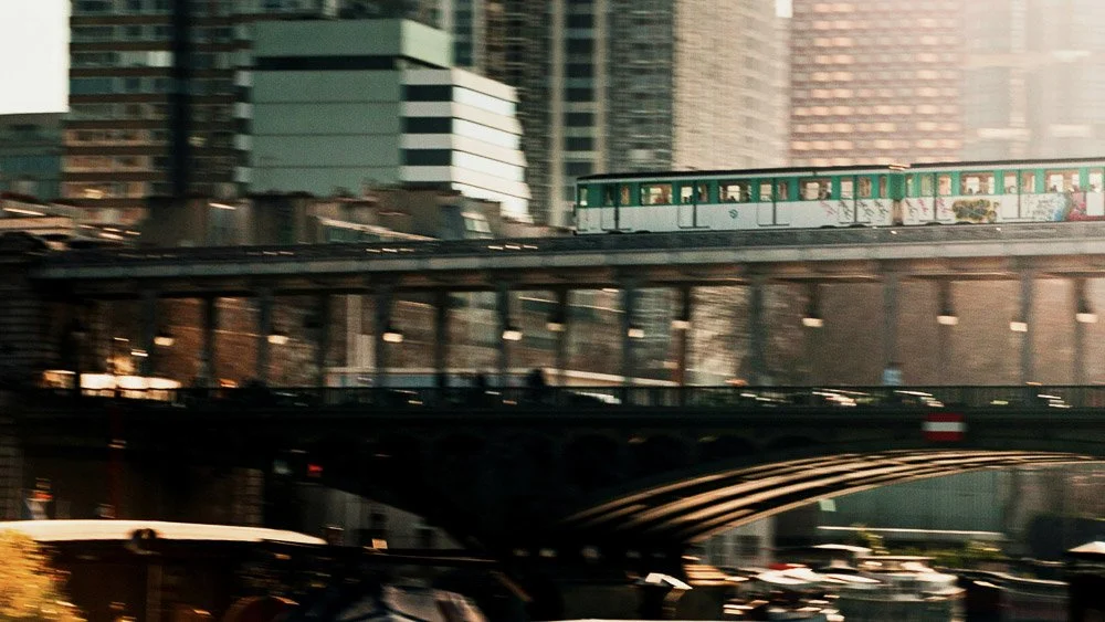 Photo d'une ville avec un métro vert passant sur un viaduc et plusieurs voitures en dessous, dans un environnement urbain avec des gratte-ciels.