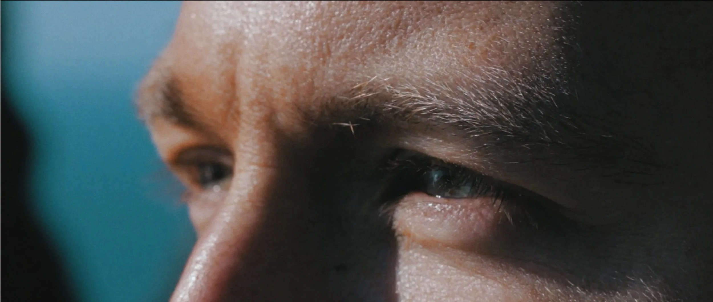 Gros plan du regard d'une personne avec un focus sur l'œil et les sourcils, détails de la peau et des cils.