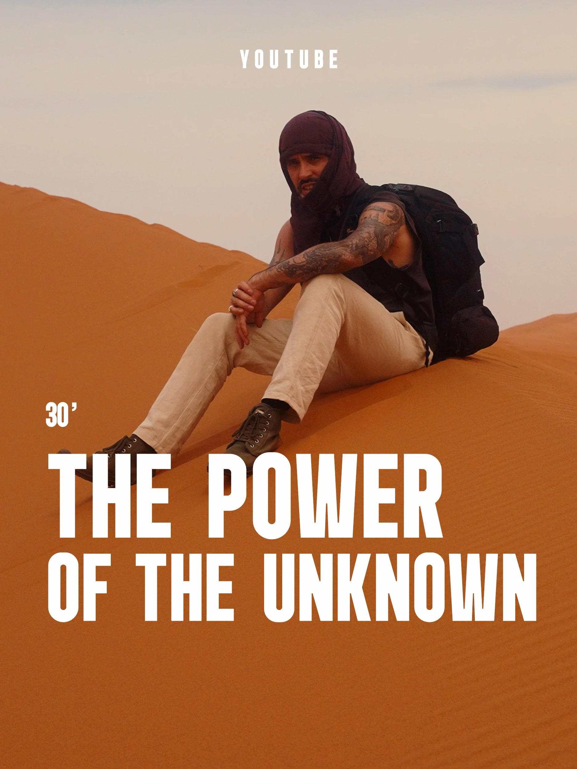 David Guersan assis sur une dune de sable, au Maroc, dans une tenue de desert, avec un sac à dos, dans un environnement désertique, sous un ciel léger