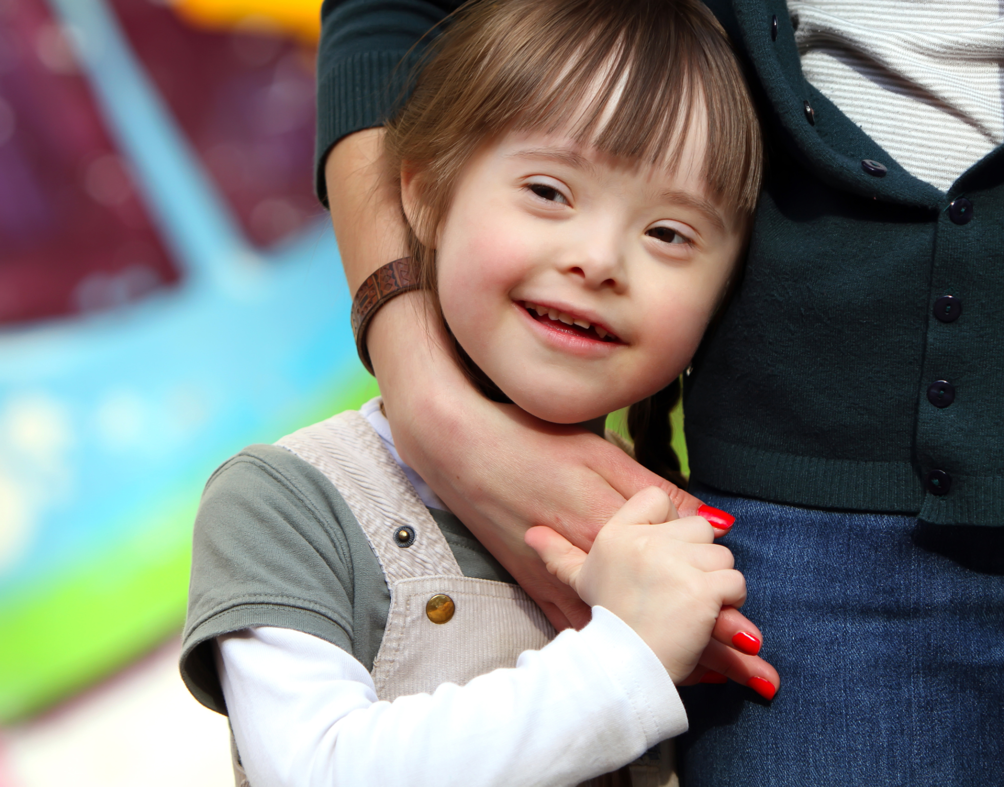 A child with down syndrome being held by a women.