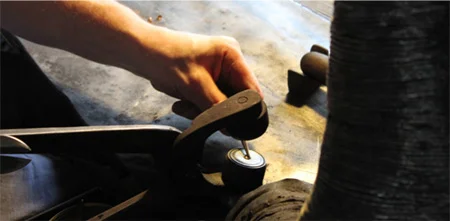 The presser sets the button shank in place and, in this case, ads a metal blank to the back of the design before opening the tongs to receive the hot glass. 