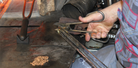 The presser shears the molten glass from the rod and then opens the mold to reveal the formed button. 
