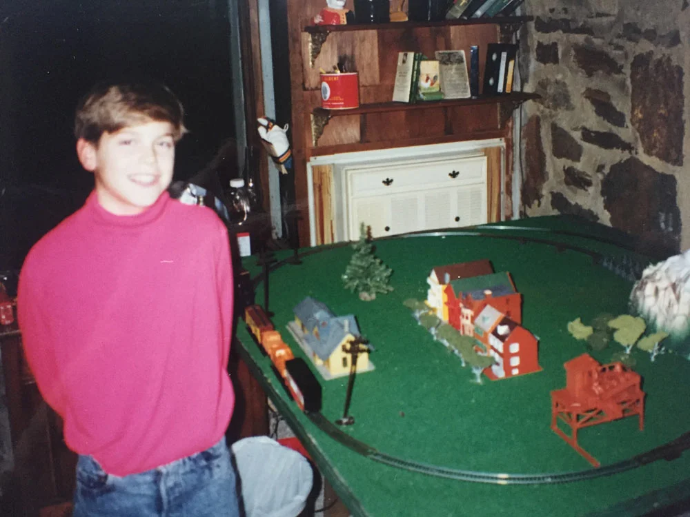 Drew posing in front of "my first urban planning attempt, a very depressing train set with models of the Pink Ladies of San Francisco." Baltimore, 1990