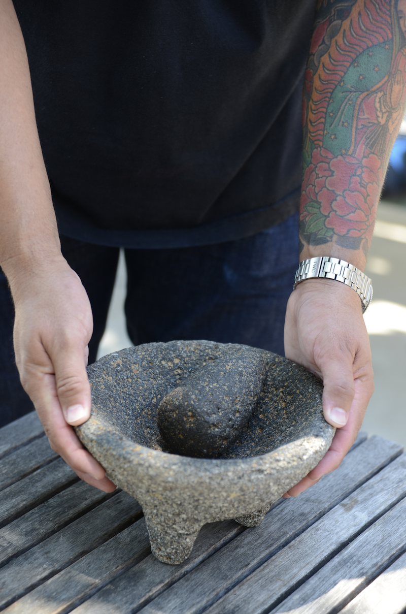 Mario Rodriguez holding his mother’s molcajete, passed down from his grandmother. The patina created by traces of ground spice is a part of its beauty. Photo by Ann Cutting.