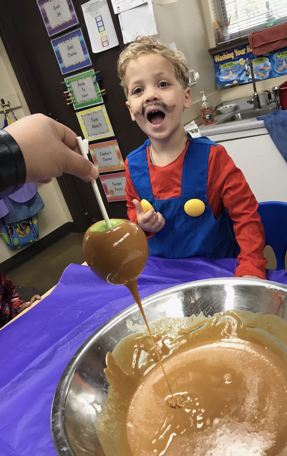 Grandchild Alex at preschool about to try his first caramel apple. 