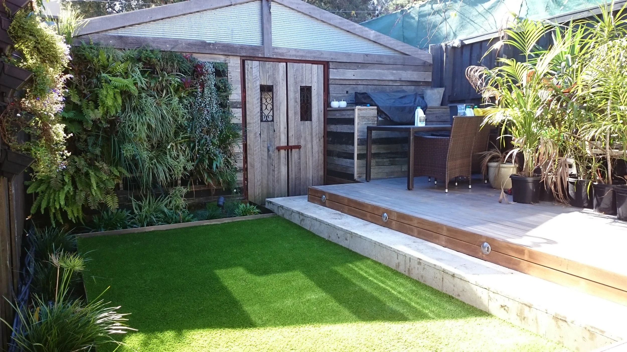 Interesting garden design for a small space. This garden has utilised all of their &nbsp;space, which is small. They have converted the fences and shed walls to gardens with their green walls. Grass is not an option for this garden as it is too shady, so the use of synthetic grass just lifts the area. Making the space look larger.