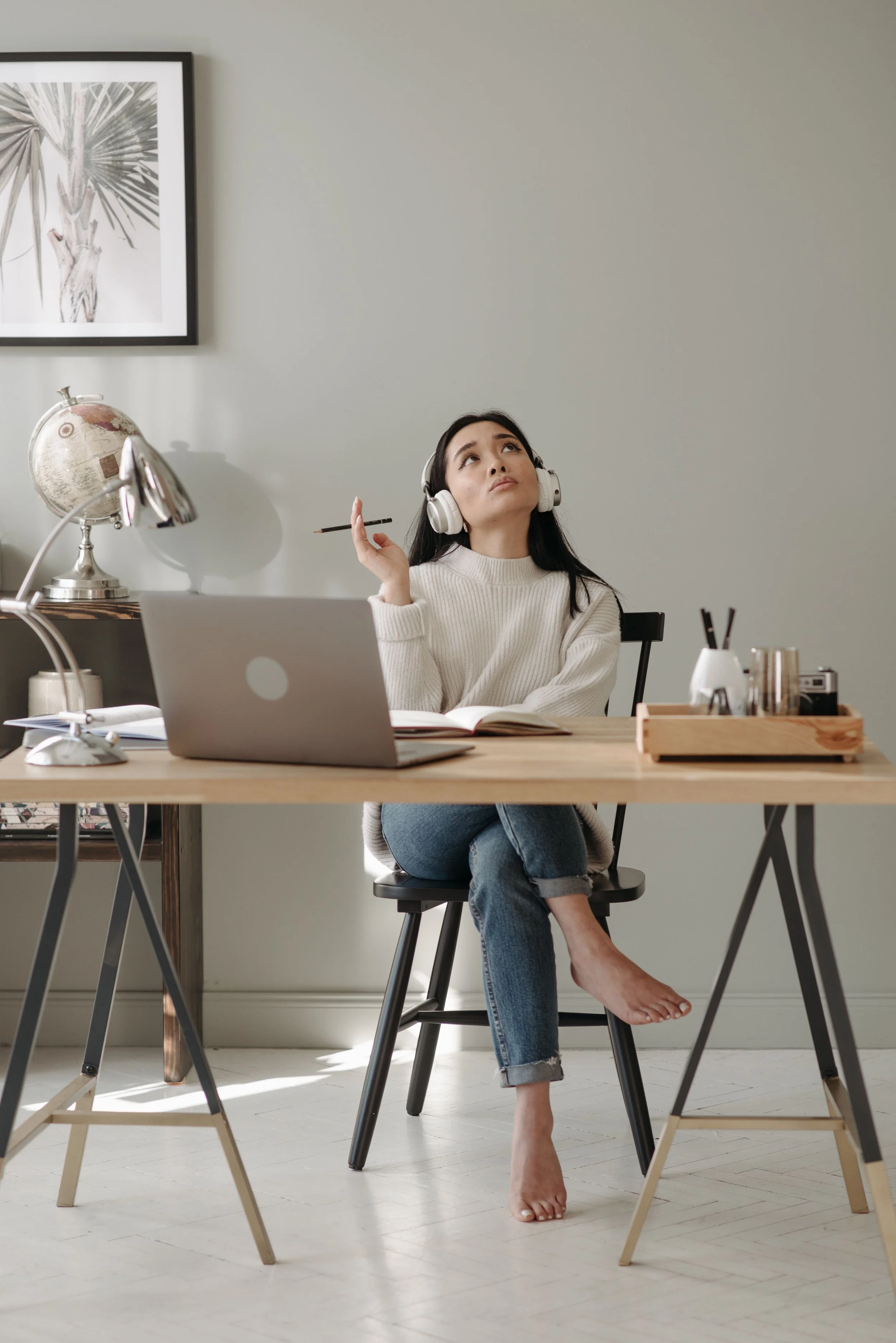 Woman sitting at a desk looking upward while lost in thought