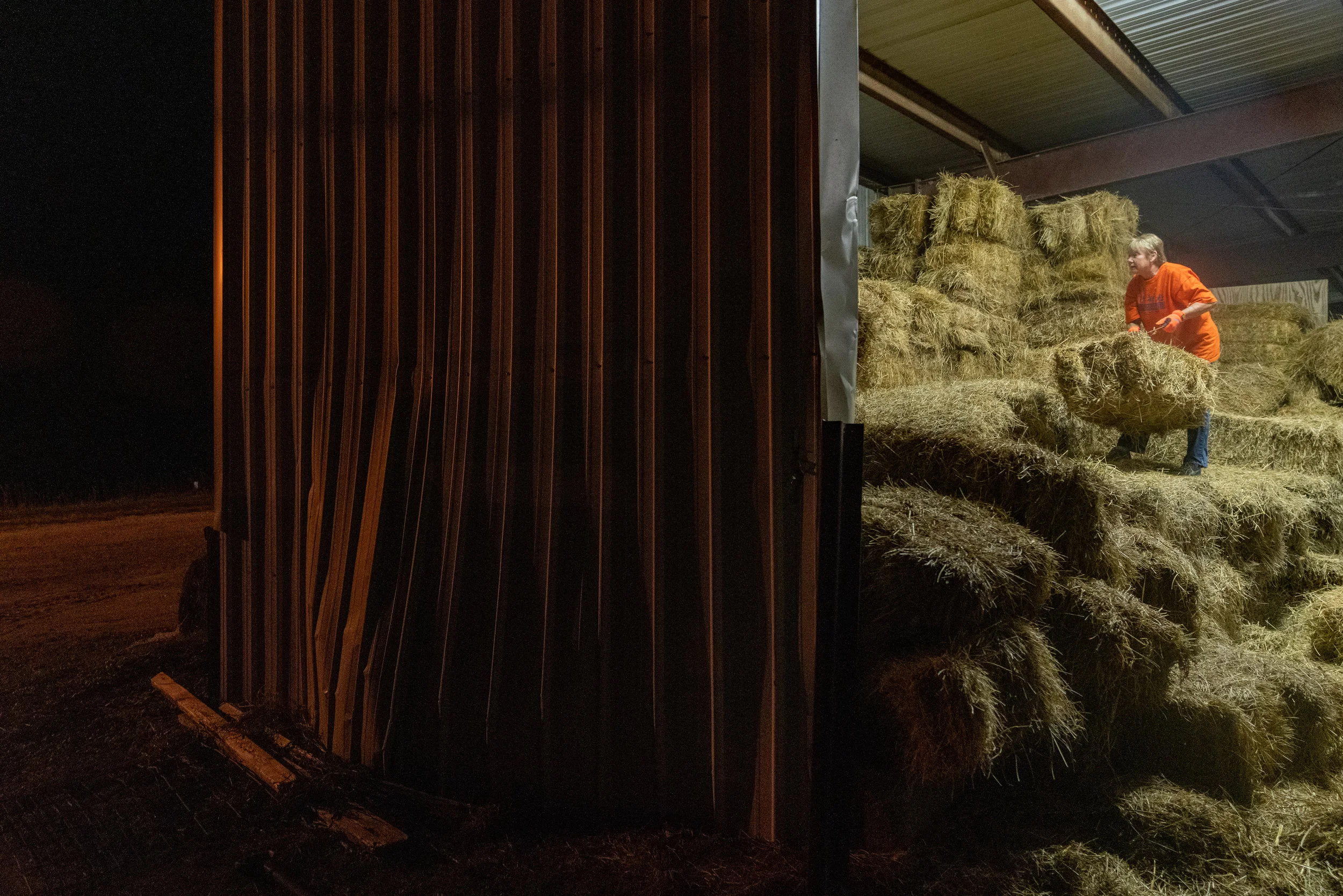Laura stacks Bales of hay into the night after having already worked a ten-hour day at her furniture store