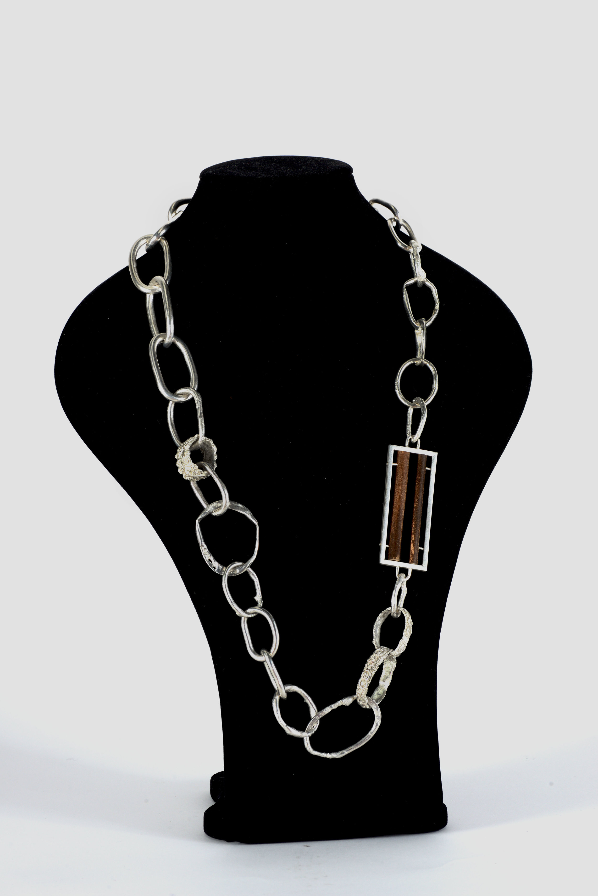 'Silver Flower' Necklace. Silver Plated Recycled Copper, Silver Rivets and Bamboo. The chain itself represents the restriction that the elephant has when it is chained to the floor as part of being a working elephant. It is made up of a mixture of very industrial looking links, as well as hammered, reticulated and pierced links to represent the abuse that the elephants face and the often occurrence of holes in the ears due to bull hooks being used. The framed bamboo represents the logging trade that many of the elephants that I volunteered with had been rescued from. The cast material represents the entertainment industry such as circuses and street performing where the elephants are usually forced to wear bright/colourful materials or costumes which cover up the abuse that they face. I named this piece 'Silver Flower' as one of the elephants at ENP rescued from the entertainment industry was called 'Dok Ngern' in Thai which translates to 'Silver Flower' in English. 