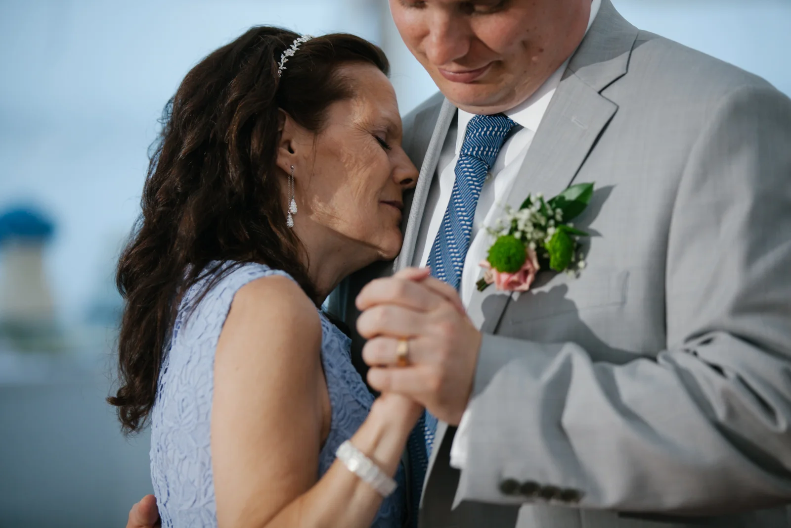 A bride and groom share an emotional moment during their wedding, holding hands closely.