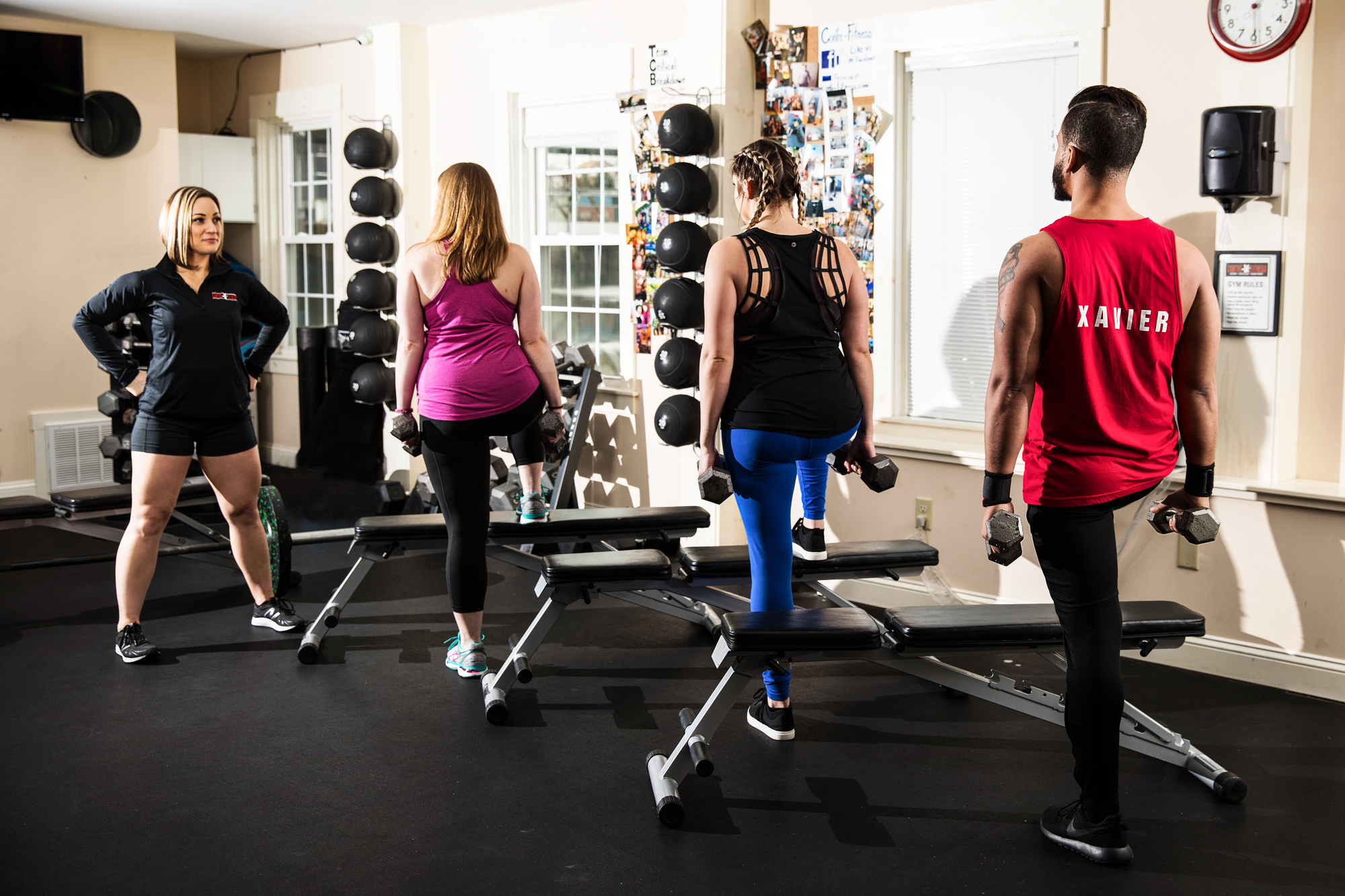 Group of four people working out with dumbbells in a gym