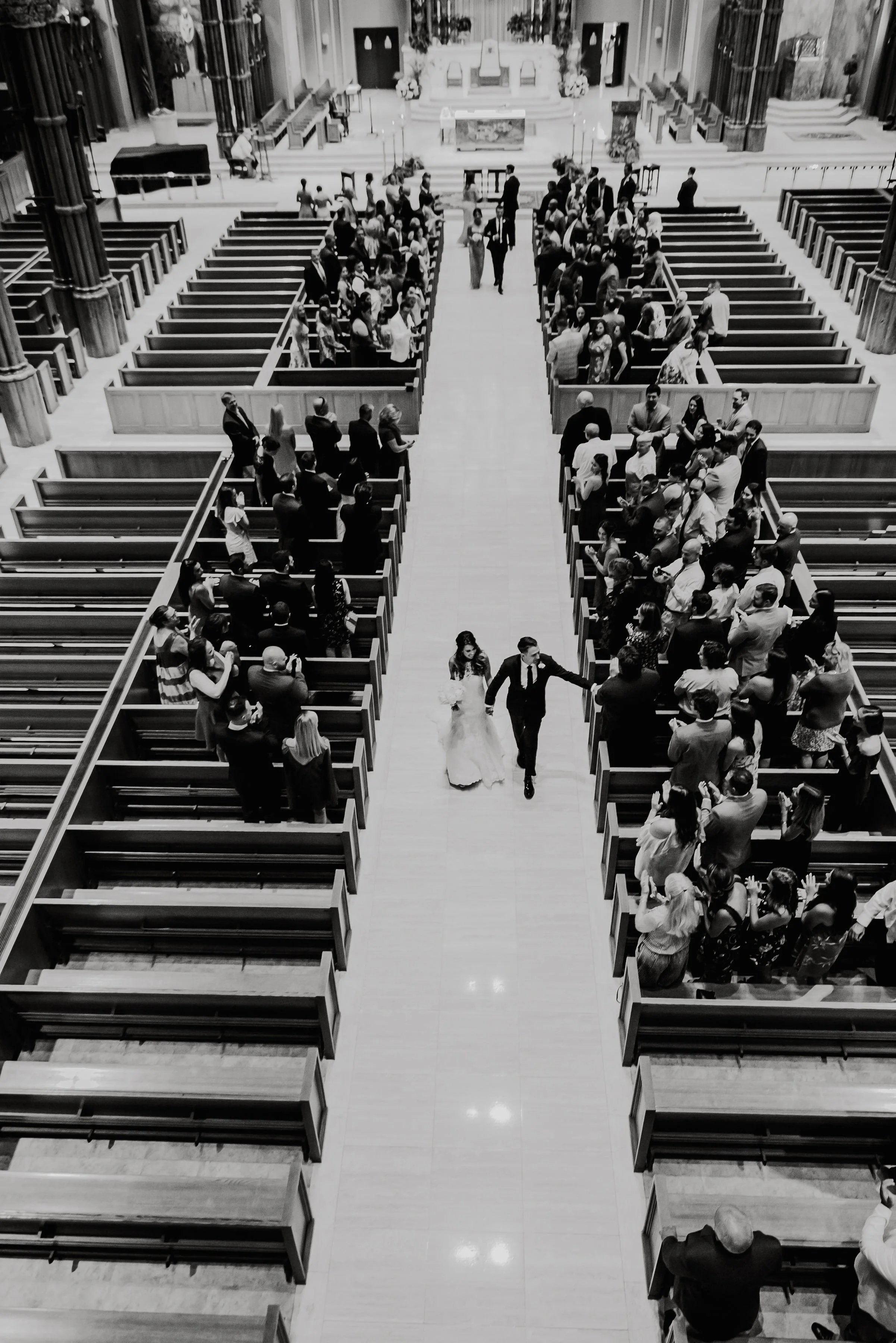 A bride and groom walking down the aisle in a church filled with guests, during a wedding ceremony.