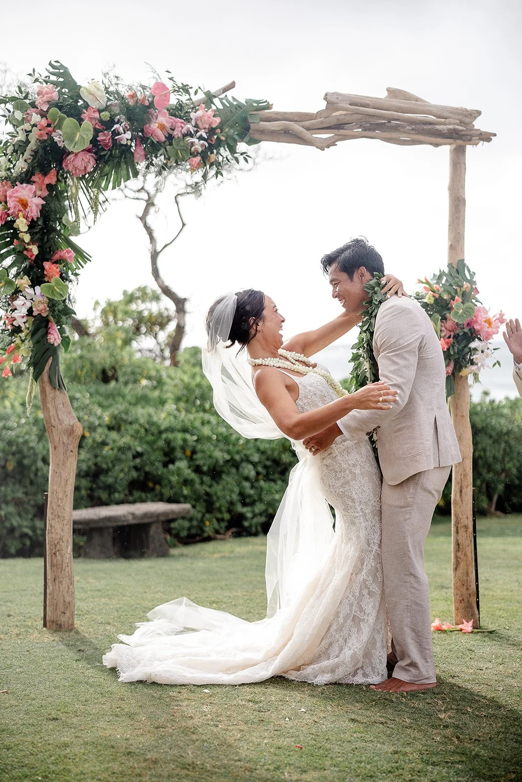 bride and groom in front of wedding arch in hawaii