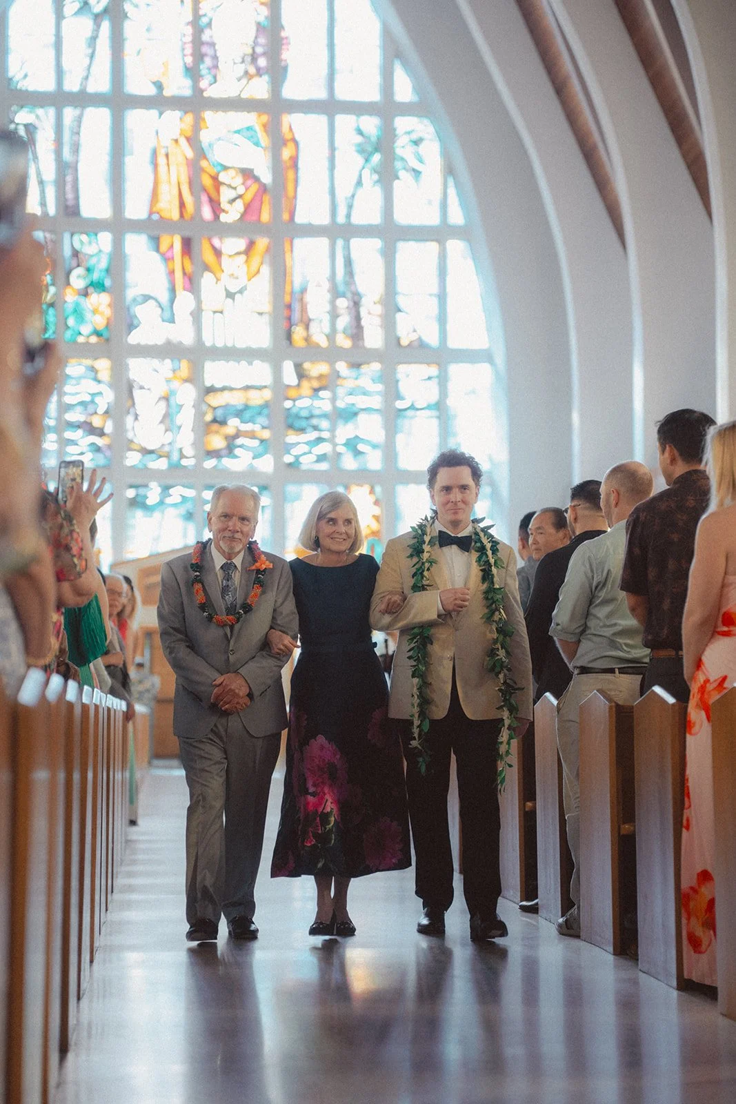 groom walking down the aisle with parents