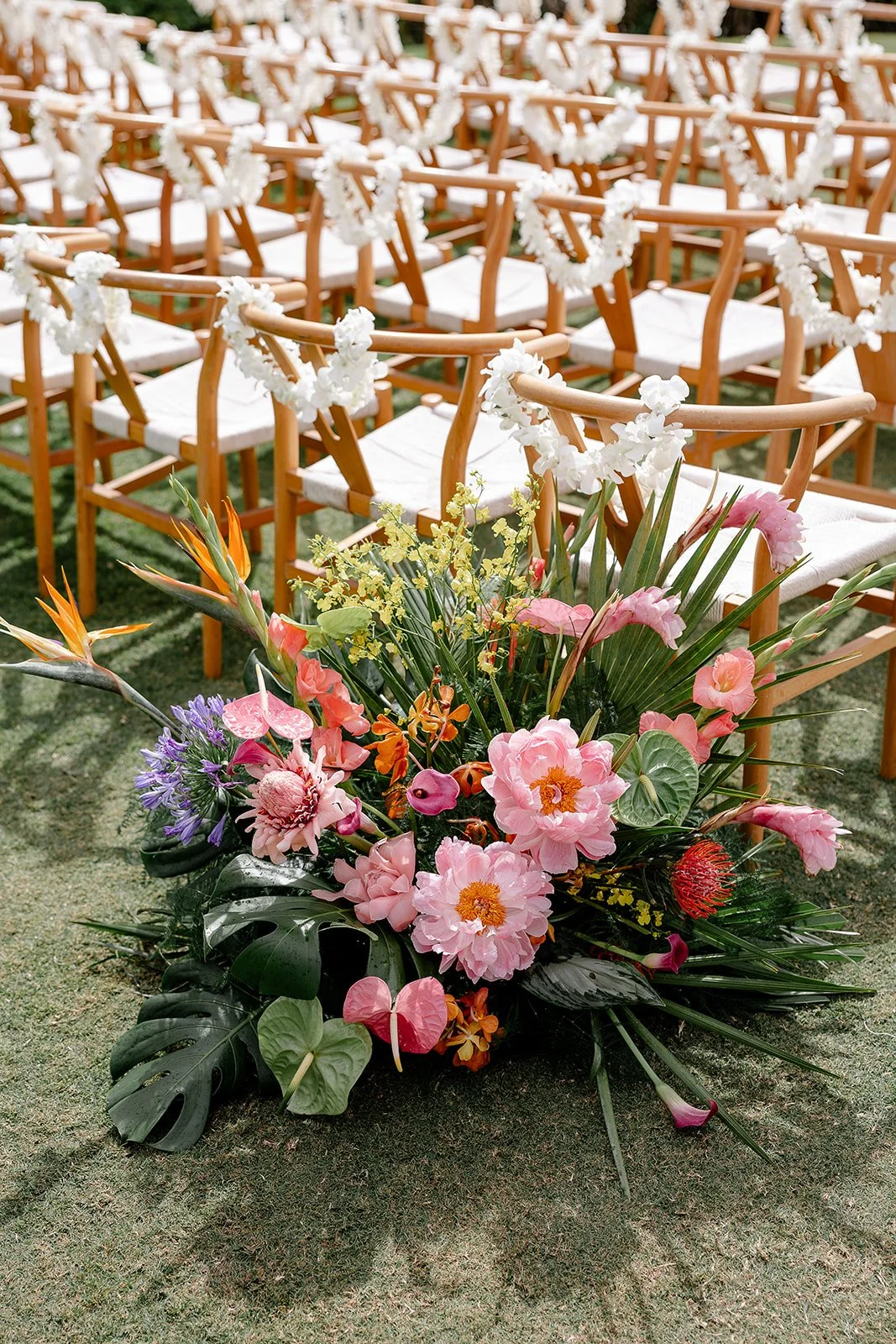 tropical ceremony arrangement with white lei on each chair