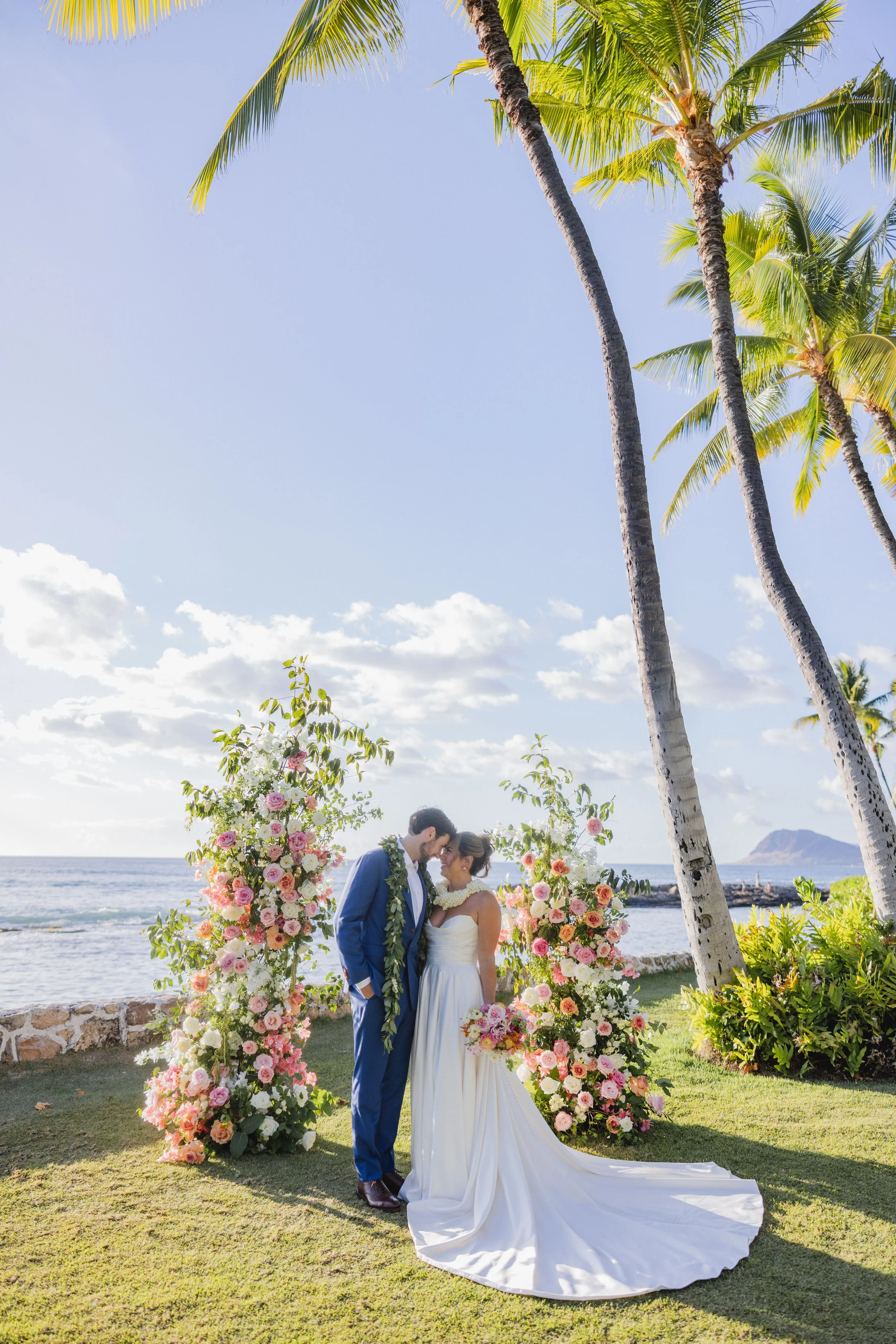 bride and groom in front of flower altar by beach in hawaii