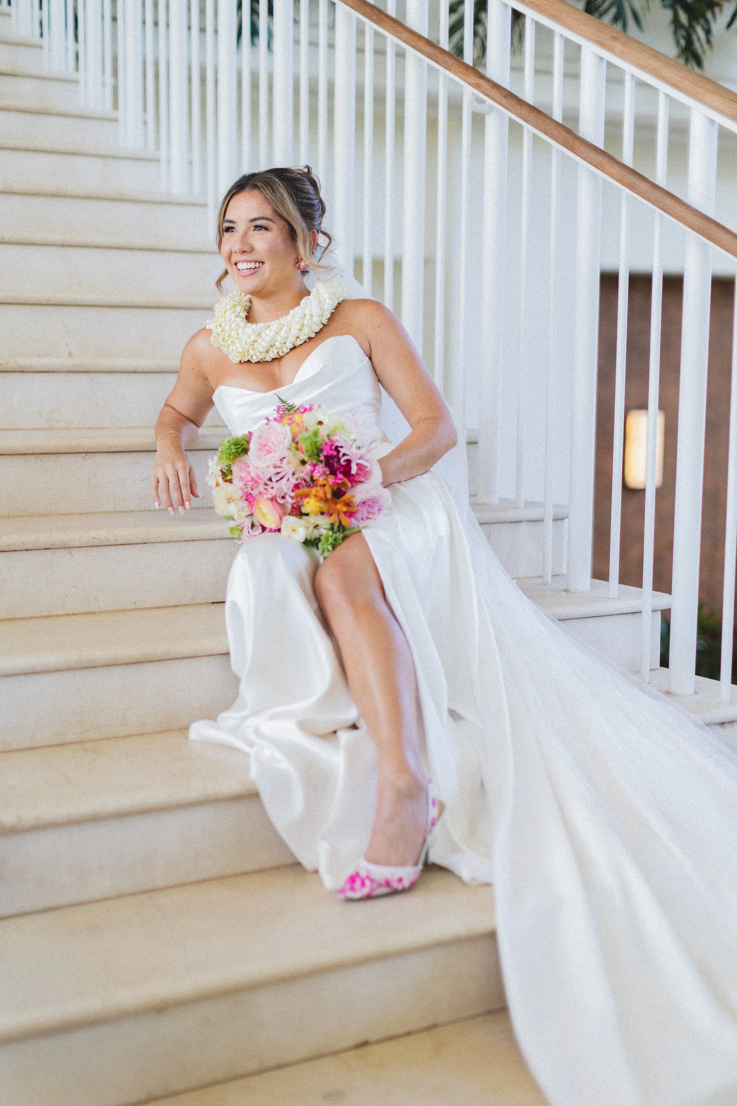 Bride sitting on stairs with pink and orange bouquet