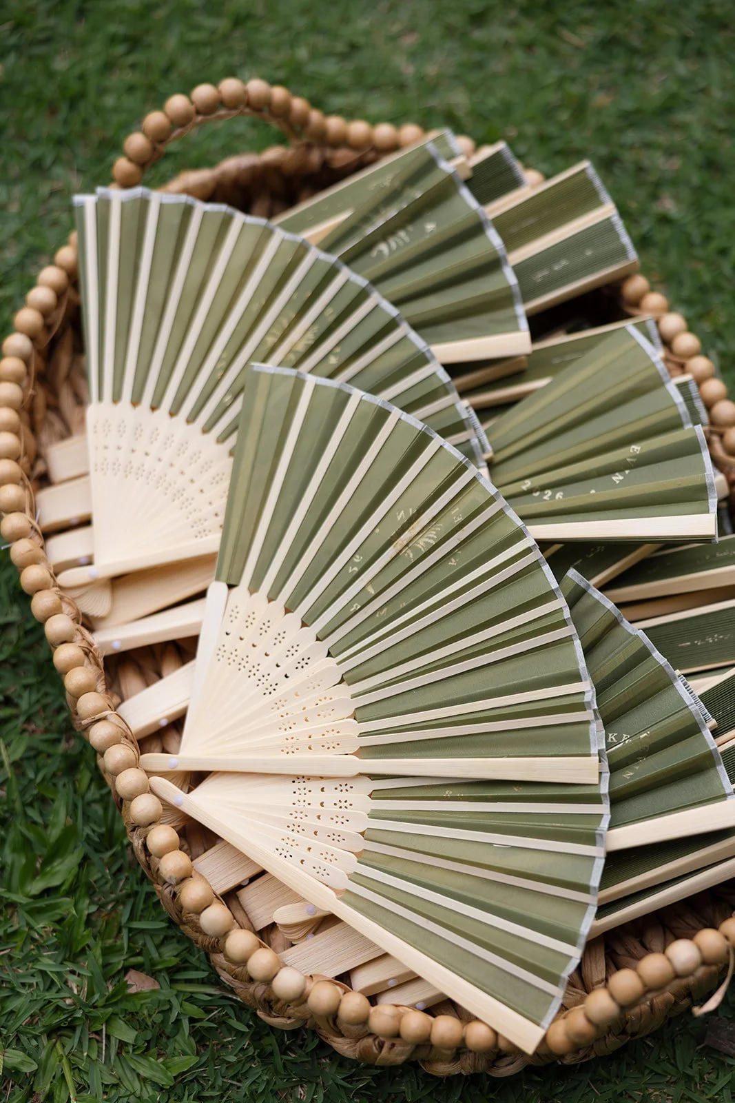 Custom green hand fans with bride and groom's names and wedding date at Paliku Gardens wedding on Oahu